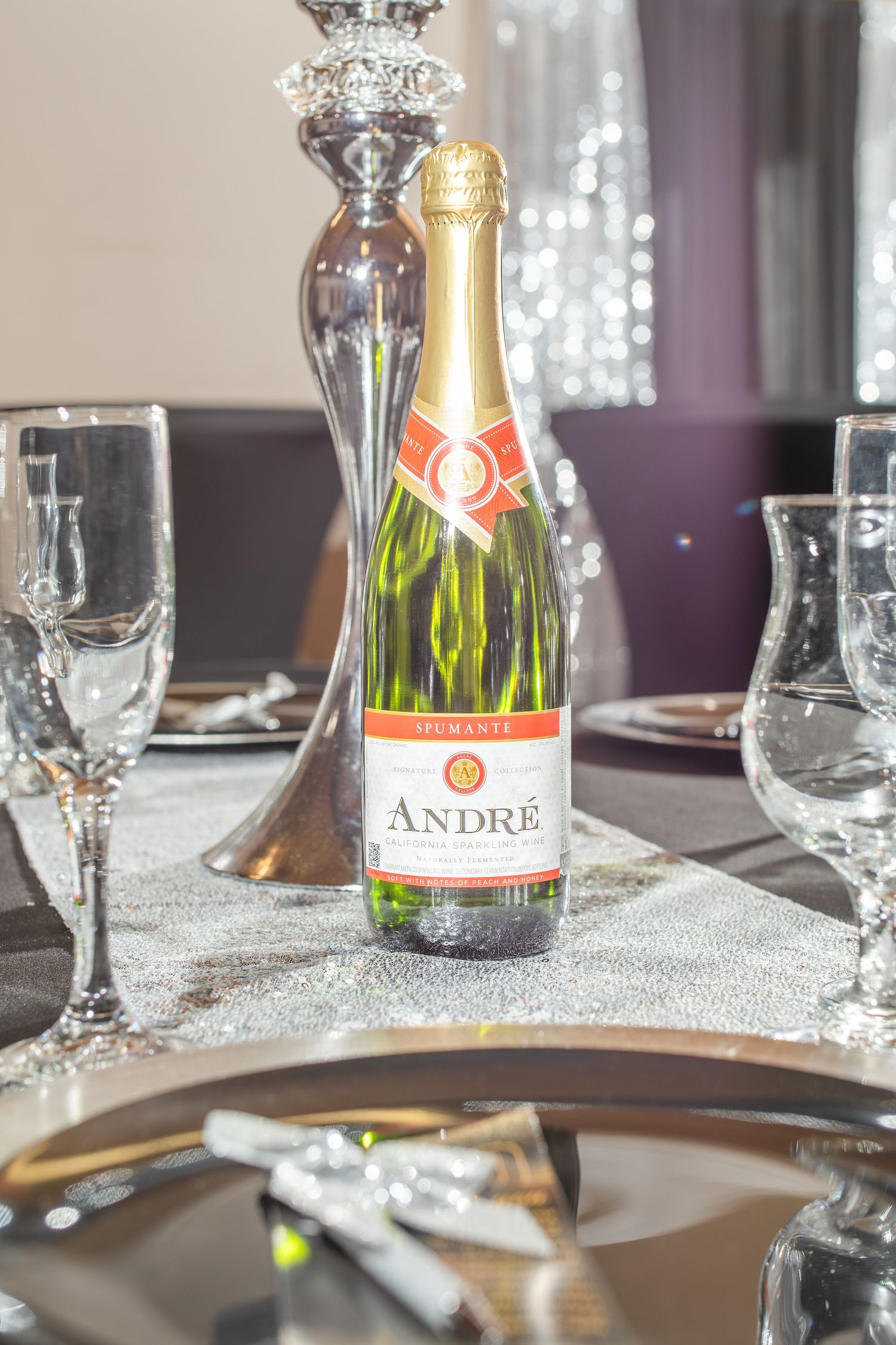 Andre Spumante champagne bottle on elegant silver table setting with crystal glasses at a formal celebration event.