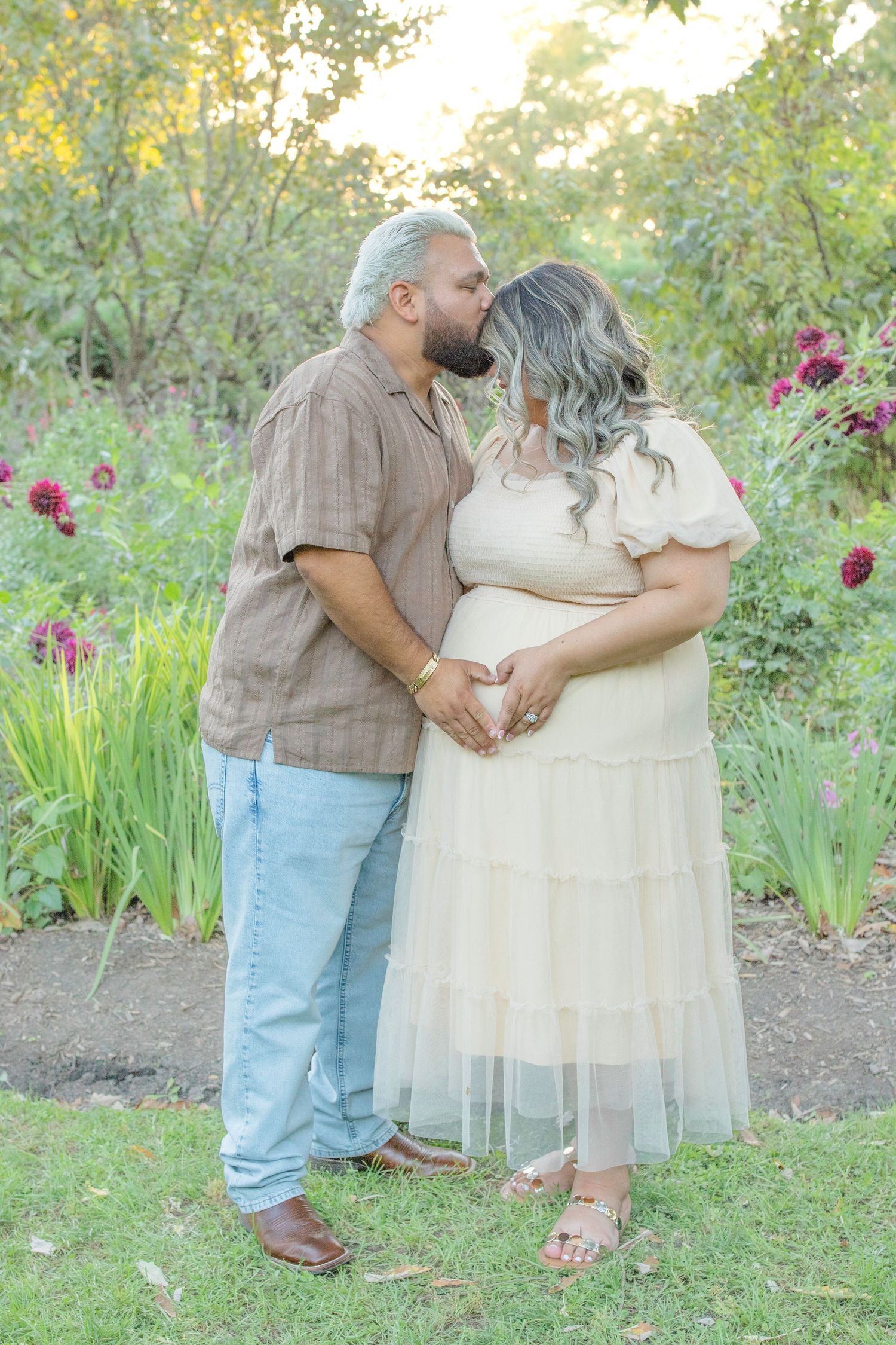A romantic couple embraces in a garden setting with blooming irises and lush greenery on a sunny spring day.