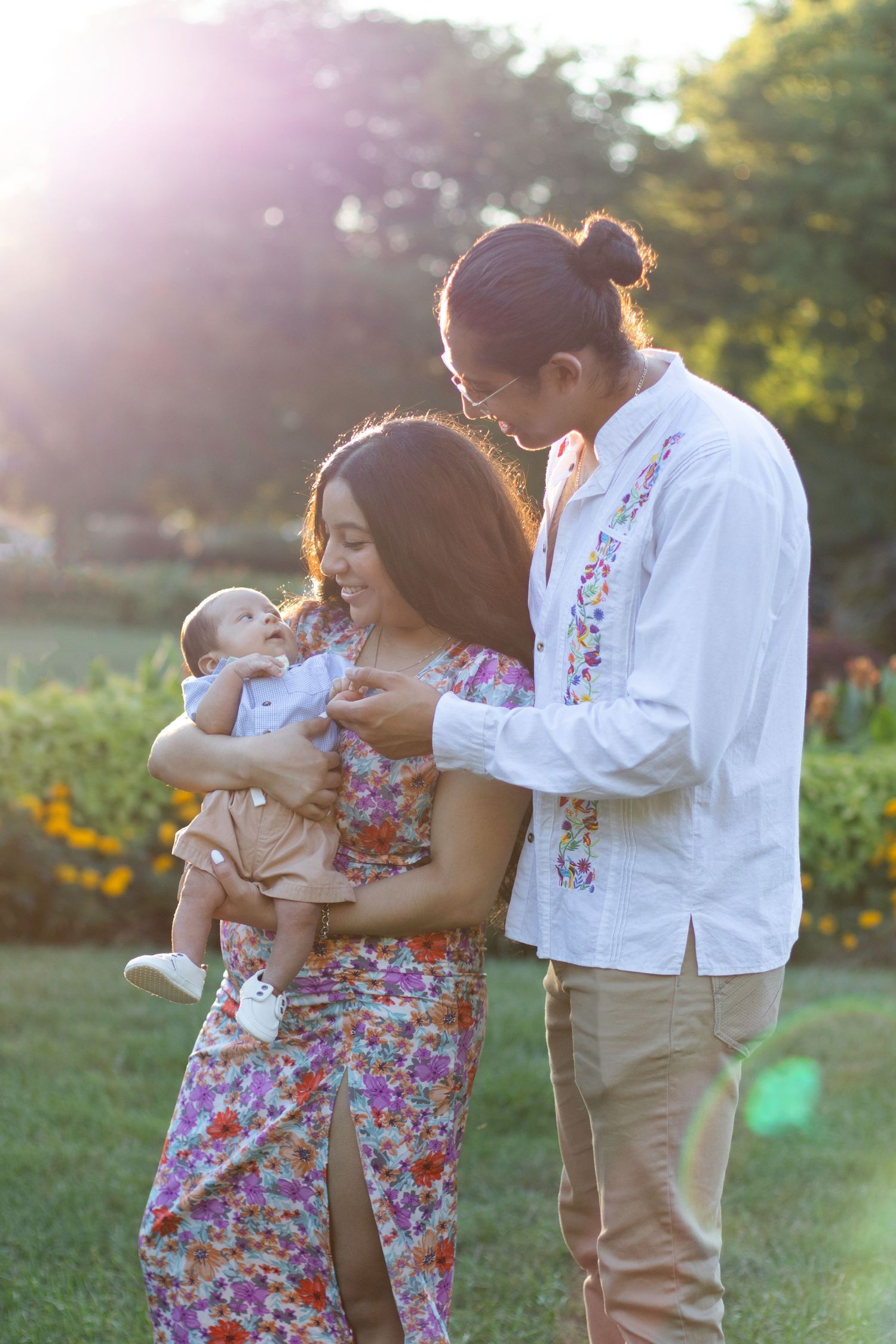 Family shares tender moment together in blooming garden during golden hour sunset.