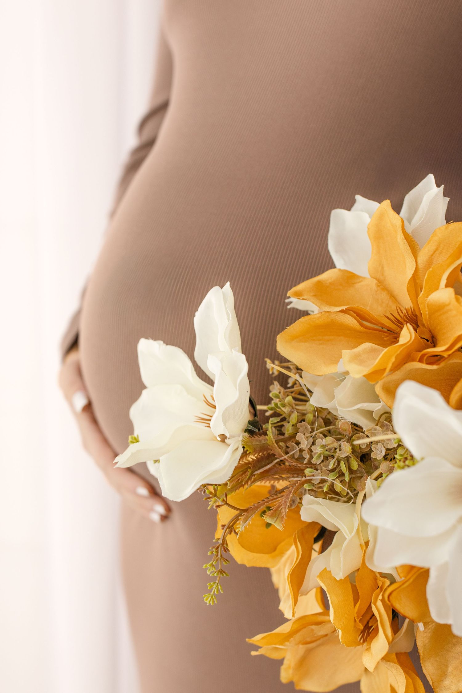 A delicate bouquet of white and orange daffodils held against a soft beige background.