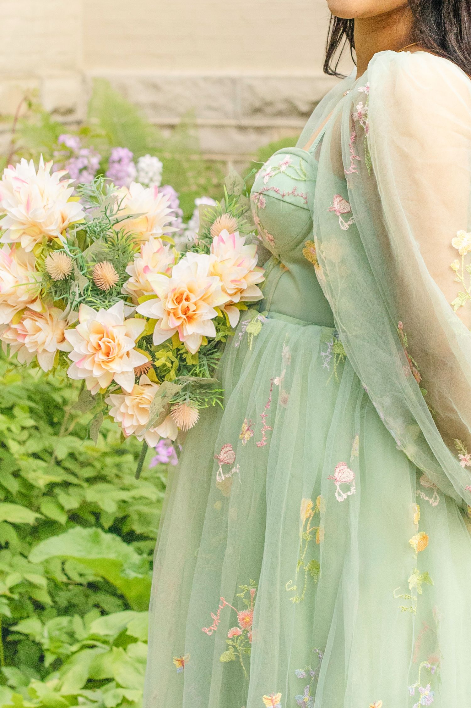 A seafoam green tulle dress adorned with delicate embroidered butterflies and peach-colored floral accents.