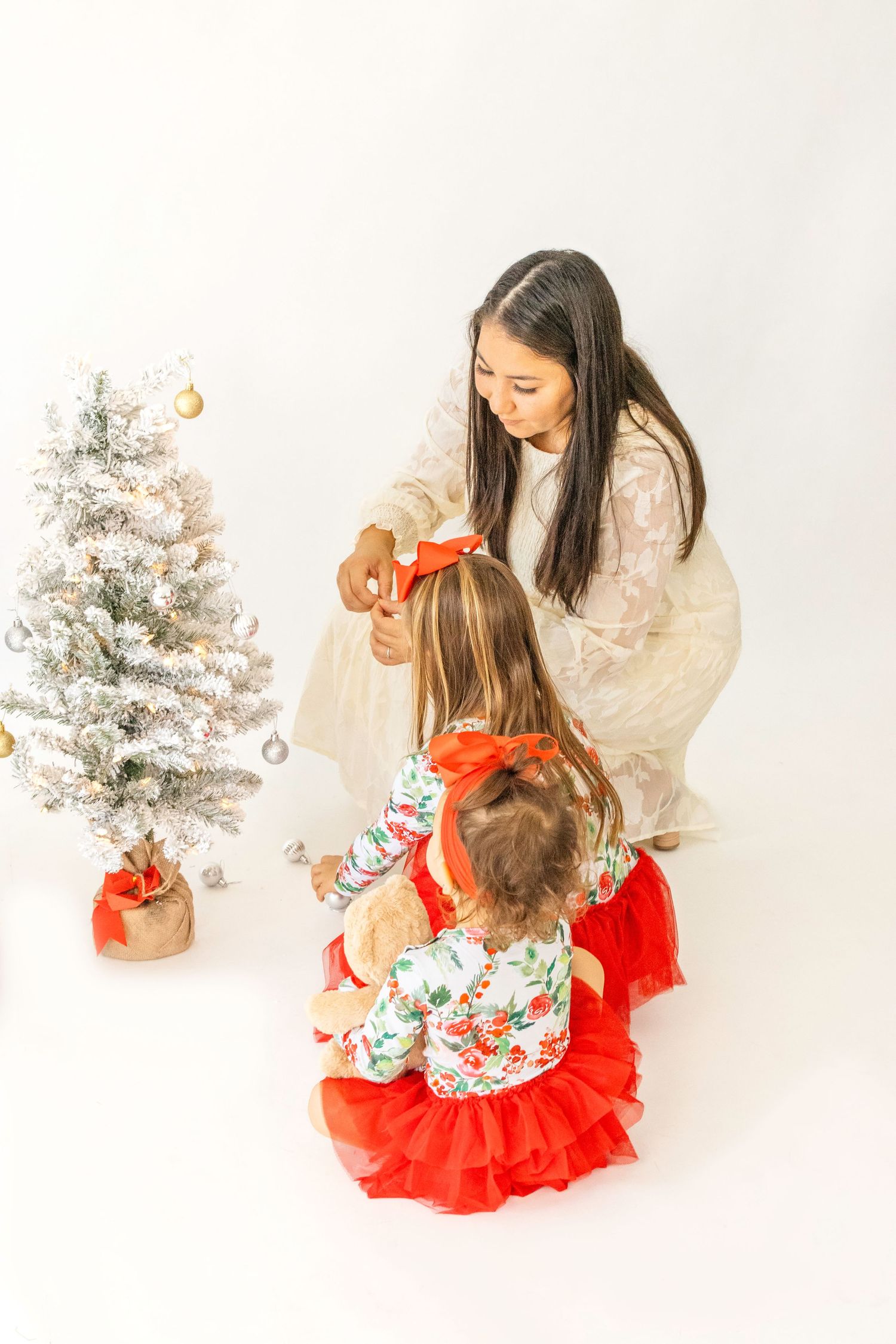 Holiday portrait session with small decorated Christmas tree and red and white festive outfits.
