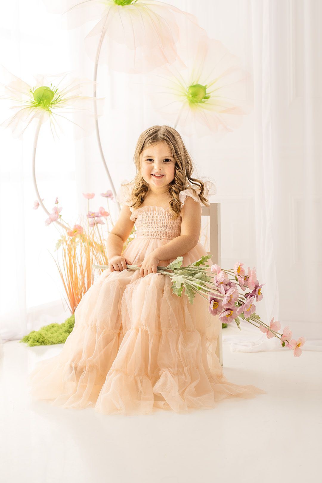 Dreamy portrait session featuring peach tulle dress with floral arrangements and soft natural lighting.