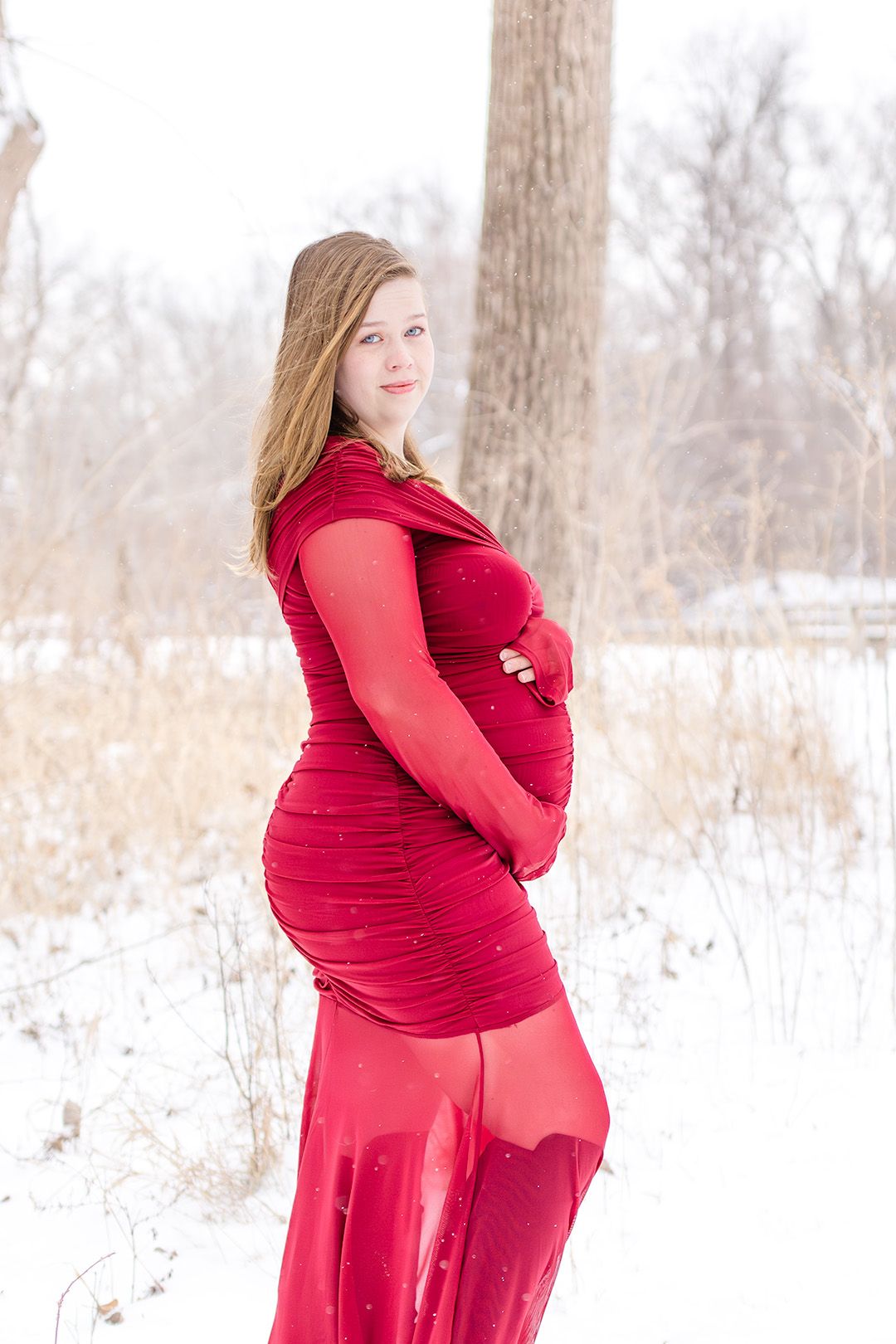 A series of maternity photos in a snowy landscape featuring a woman in a flowing red dress.