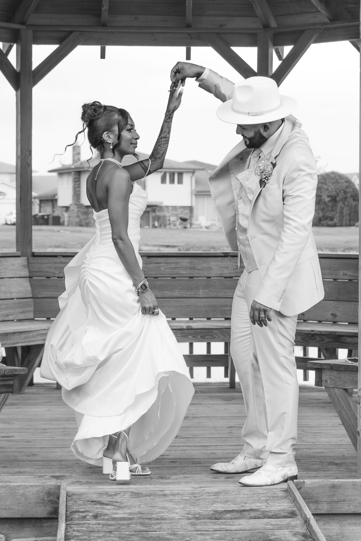 Black and white photo series showing dancers in white clothing performing graceful moves on a wooden deck platform.