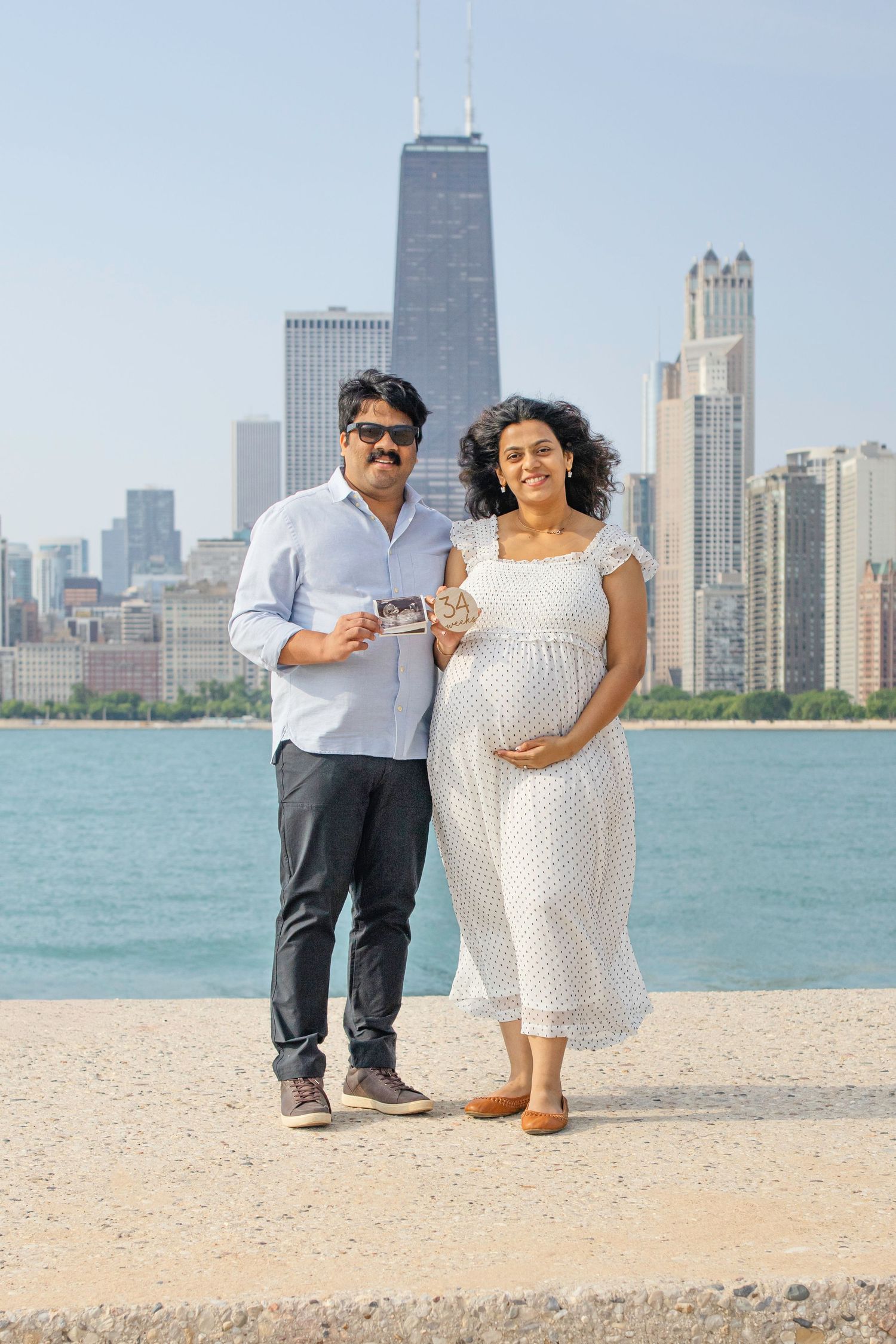 A couple poses on North Avenue Beach with the iconic Chicago skyline and Lake Michigan in the background.