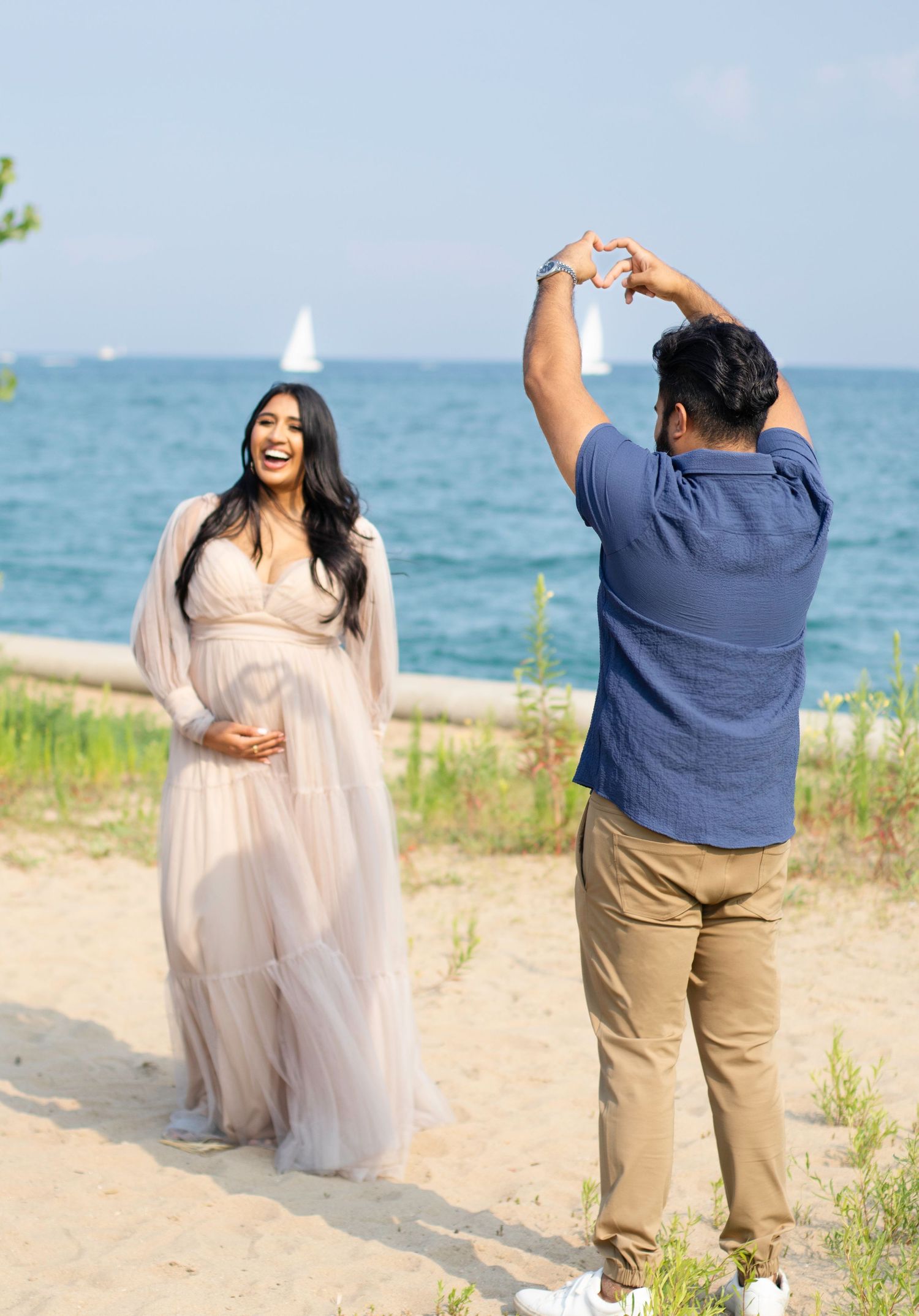 Couple forms heart shape with hands against Lake Michigan and Chicago skyline backdrop.