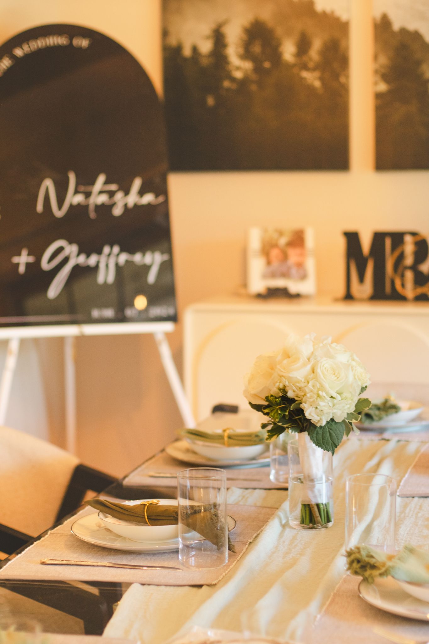Wedding reception table setting with black welcome sign and floral centerpiece.