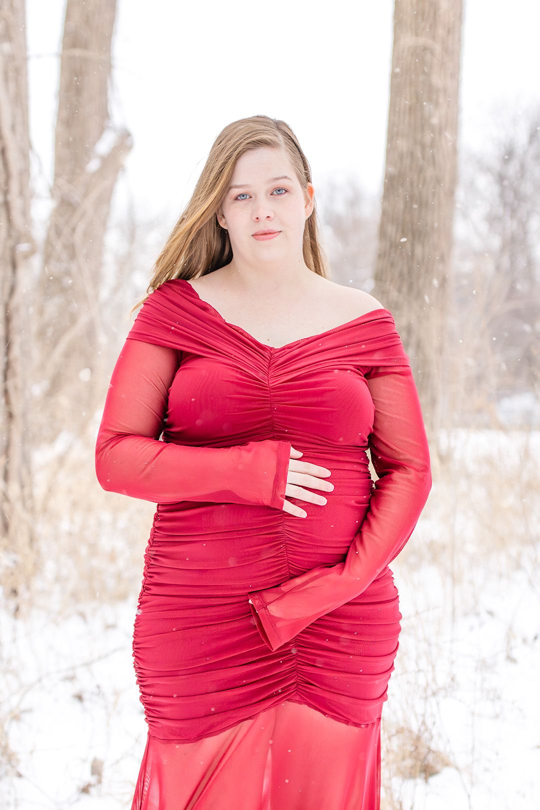 A series of winter maternity photos showing a flowing red wrap dress against a snowy forest backdrop.