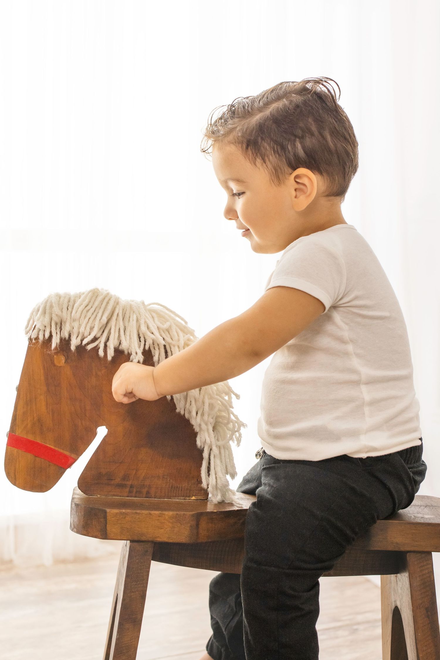 Small child plays on a wooden rocking horse toy against a white backdrop in a sequence of action shots.