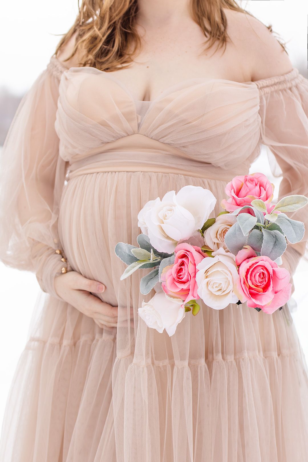 Close-up details of a blush pink maternity dress adorned with pink and white floral accents.