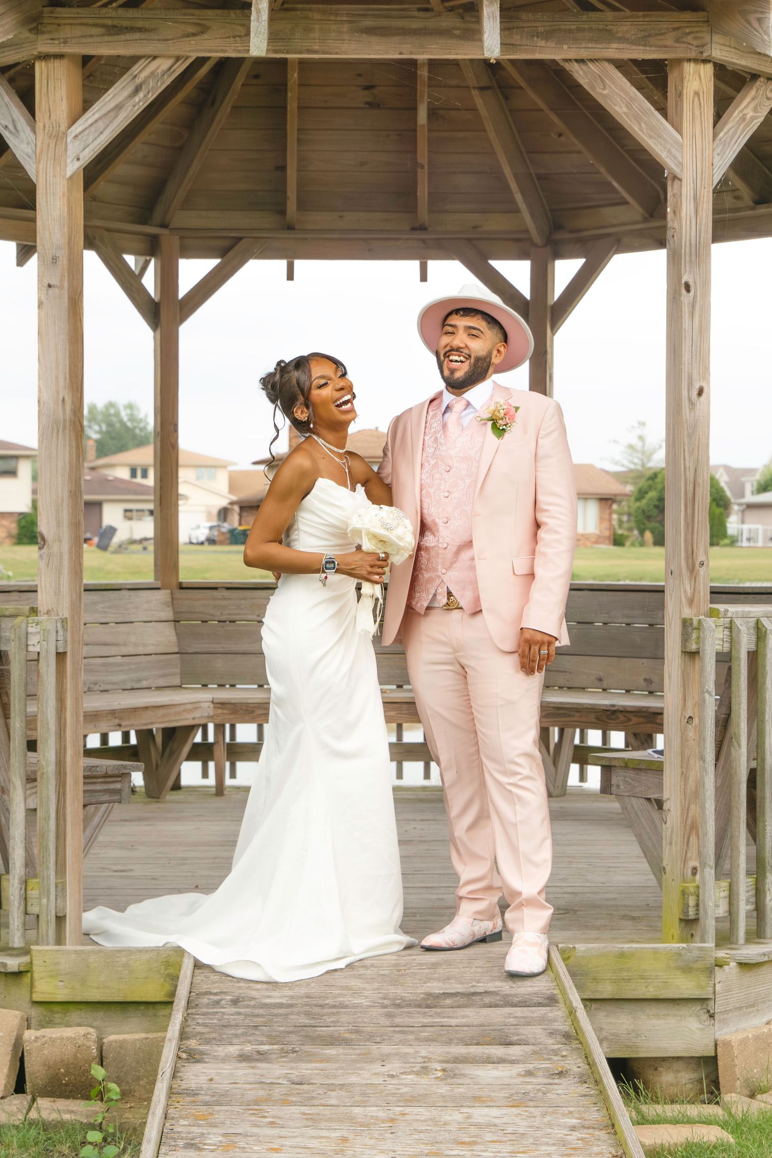 Wedding couple shares romantic moments under a rustic wooden gazebo.