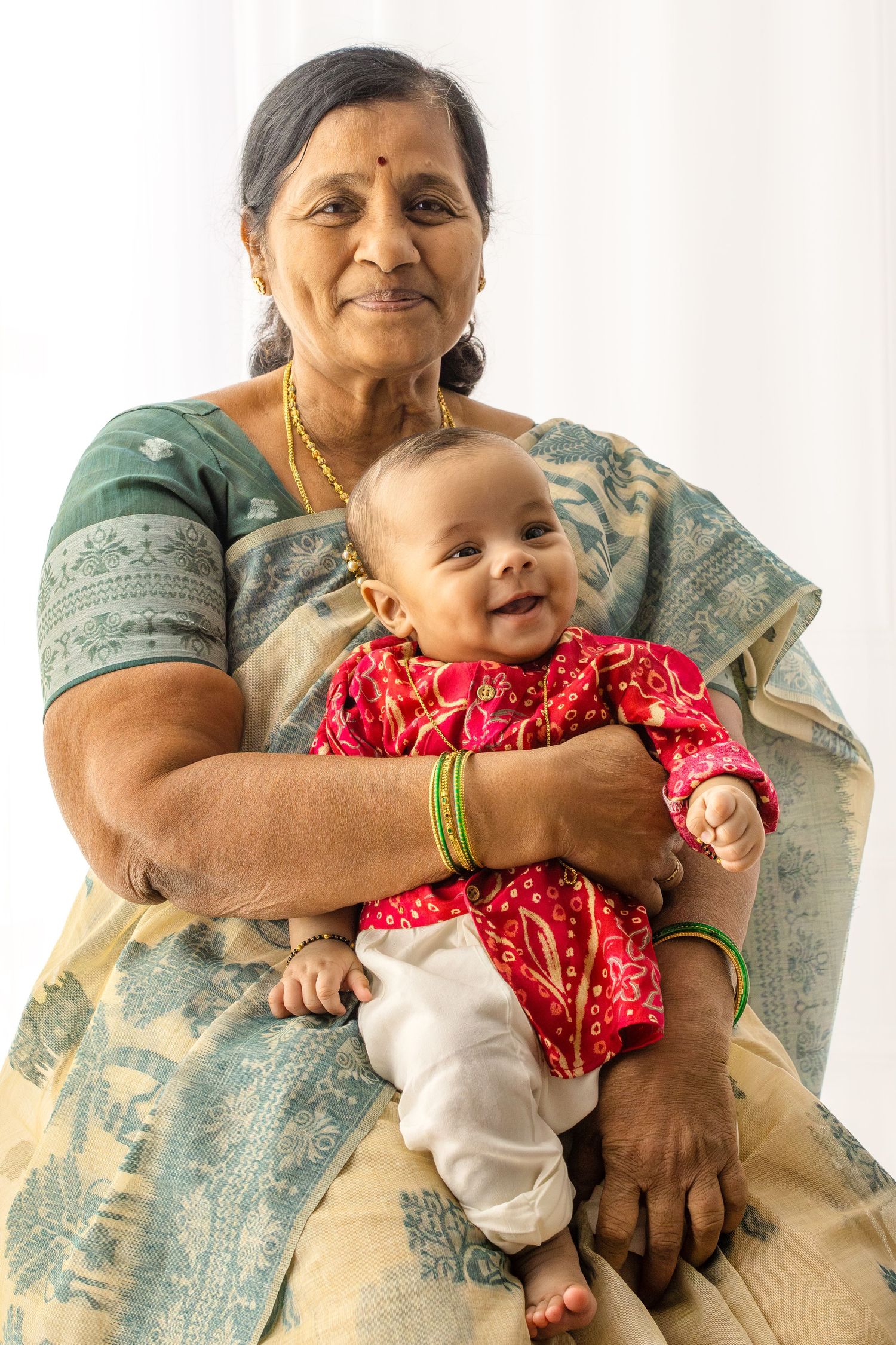 A series of photos showing a baby in a red outfit being held and embraced by someone wearing a light blue sari.