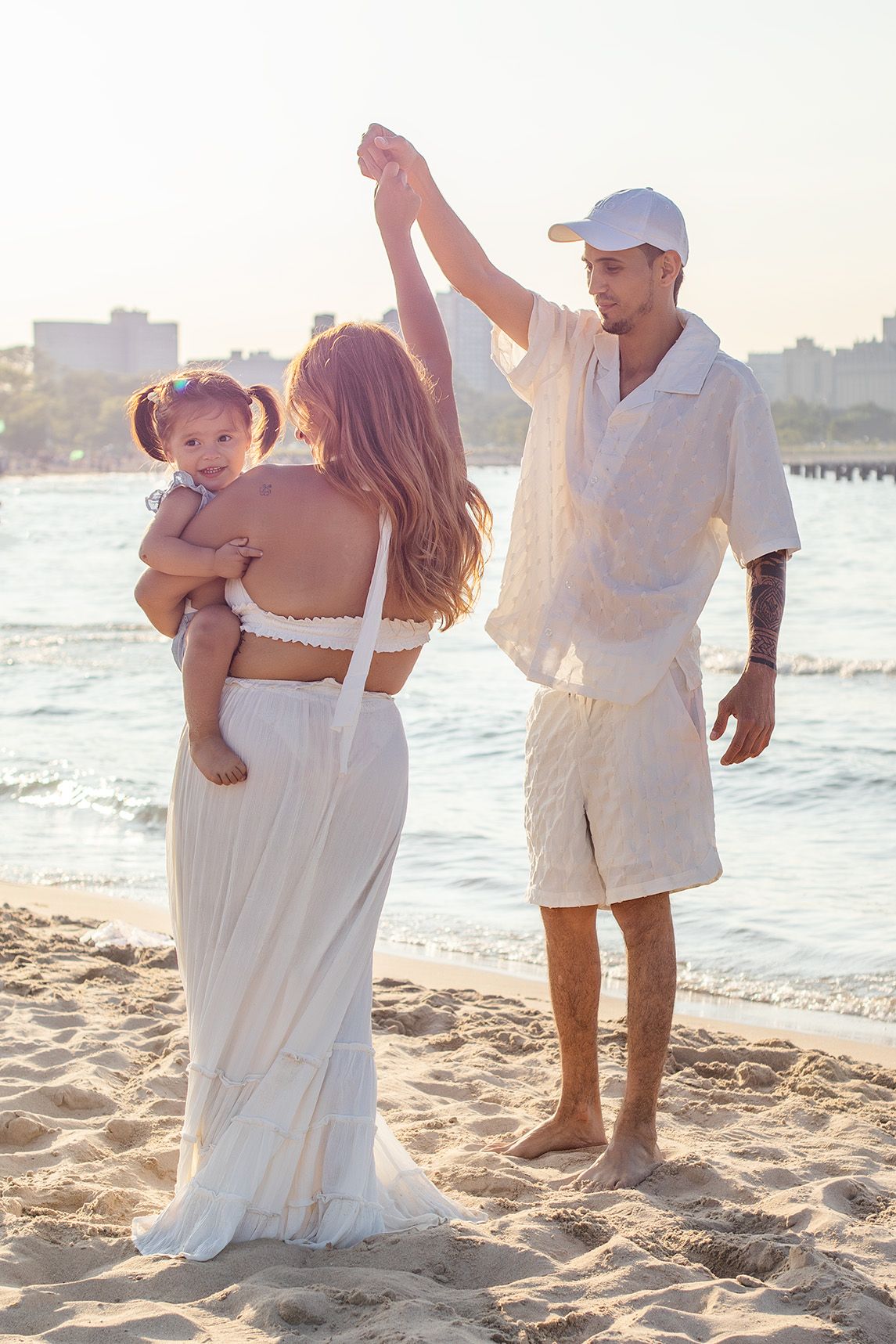 Young couple with baby enjoying a romantic sunset stroll on a sandy beach.