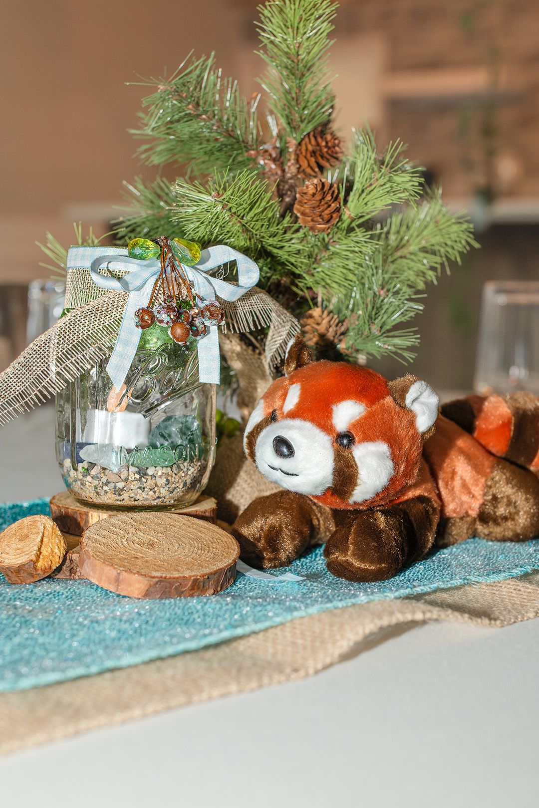 Rustic holiday decor featuring evergreen branches, pinecones, and blue ribbons arranged on a textured surface.