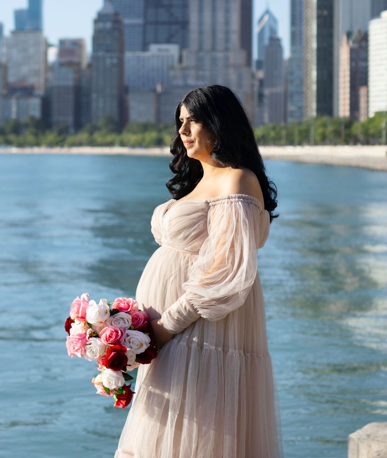 Maternity portrait with pink roses against Chicago skyline backdrop.
