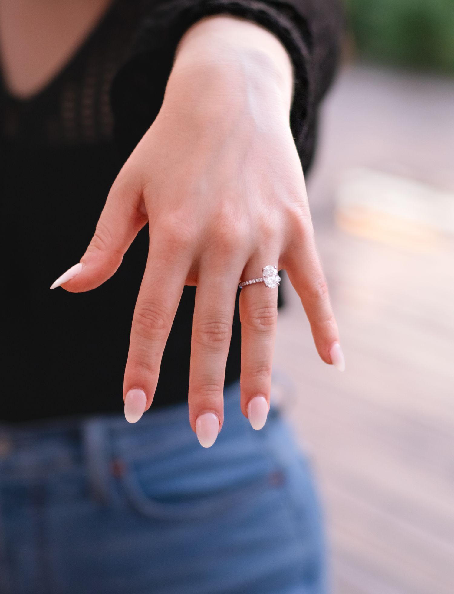 Close up of engagement ring on manicured hand with light pink nails.