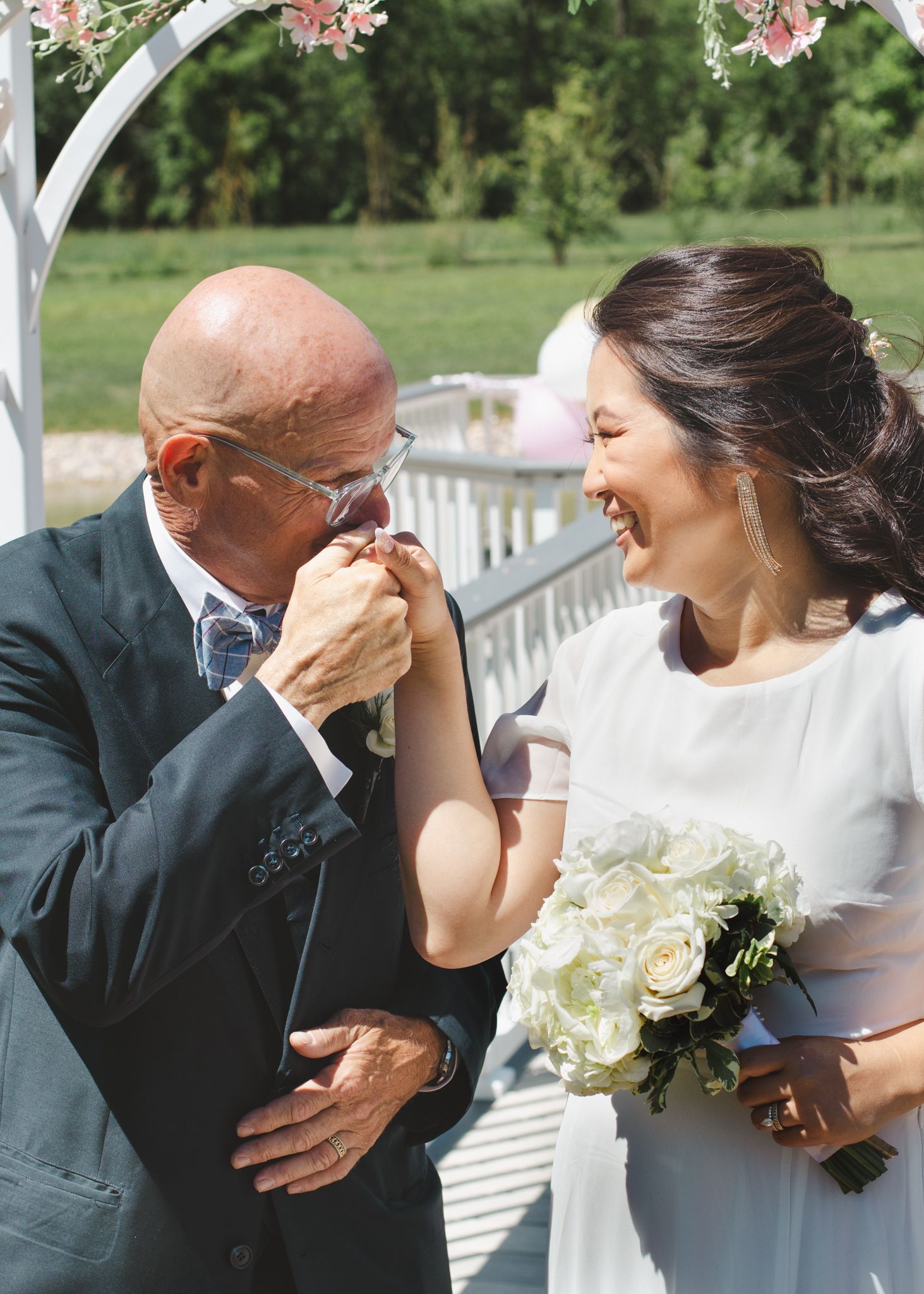 A tender moment shared during an outdoor wedding ceremony under a floral arch.