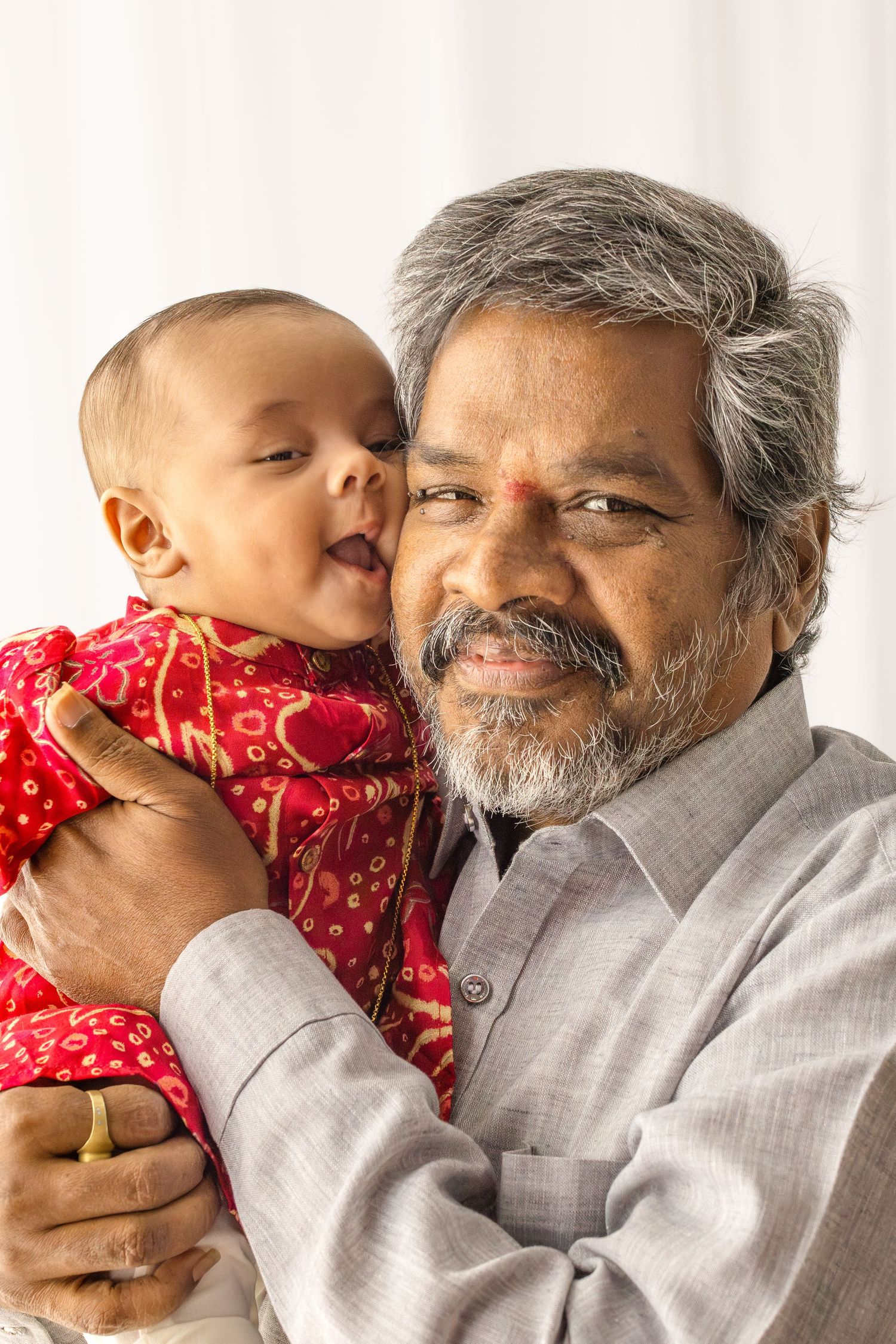 A heartwarming sequence of photos showing a tender moment between a bearded senior in gray and a small baby in red.