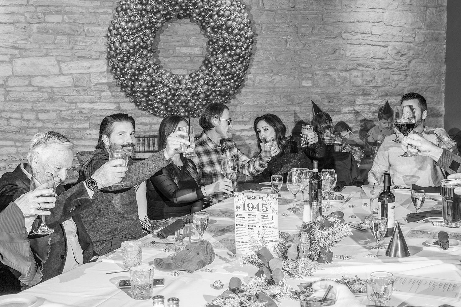 A black and white panoramic photograph showing people gathered around tables at a formal dining event.
