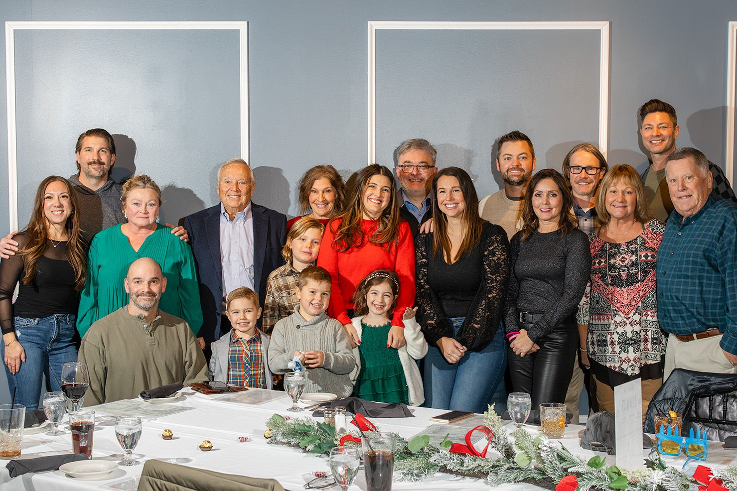 A panoramic collage of people gathered around tables at a festive holiday celebration.