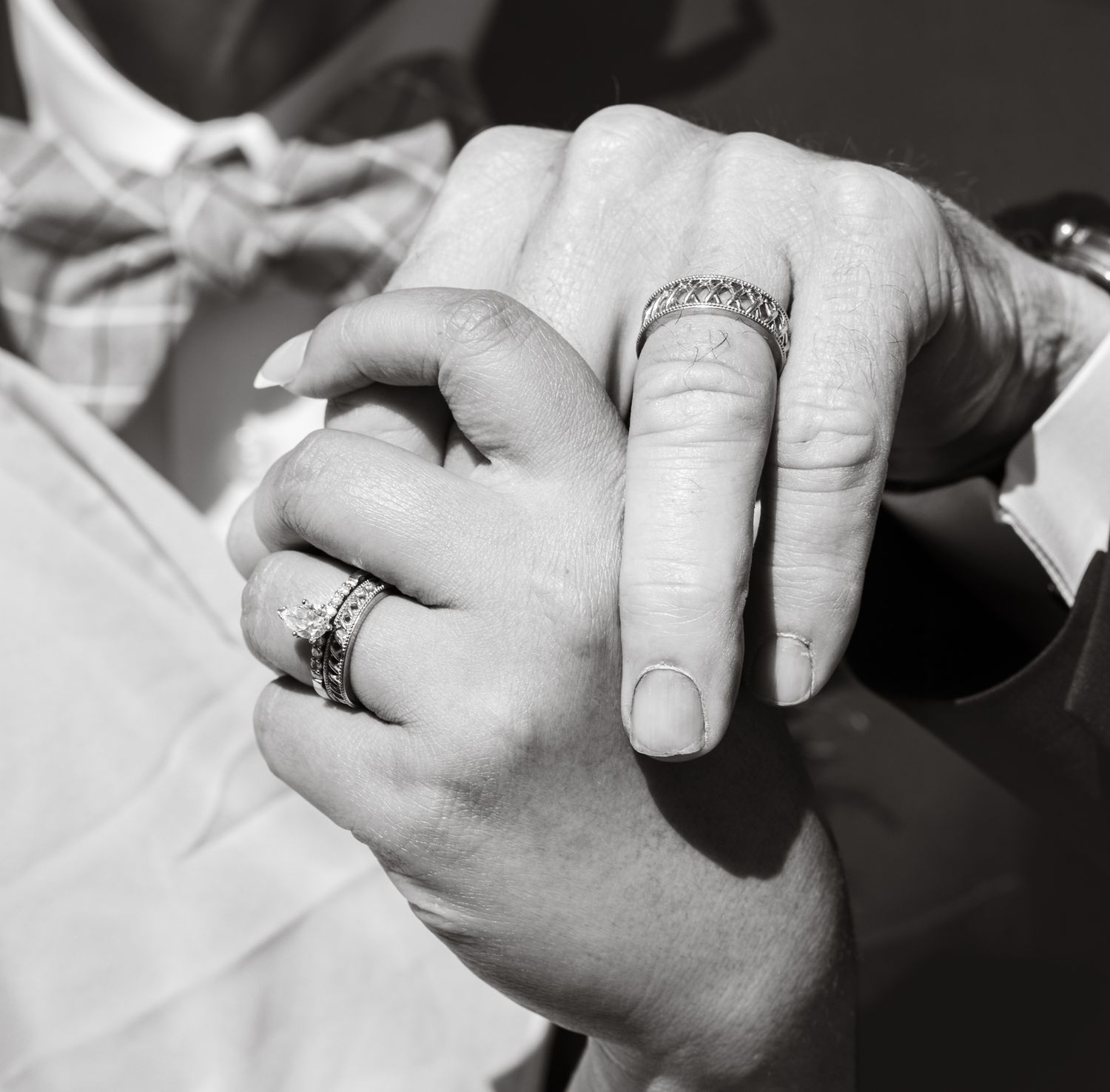 Black and white close-up of hands with wedding rings intertwined.