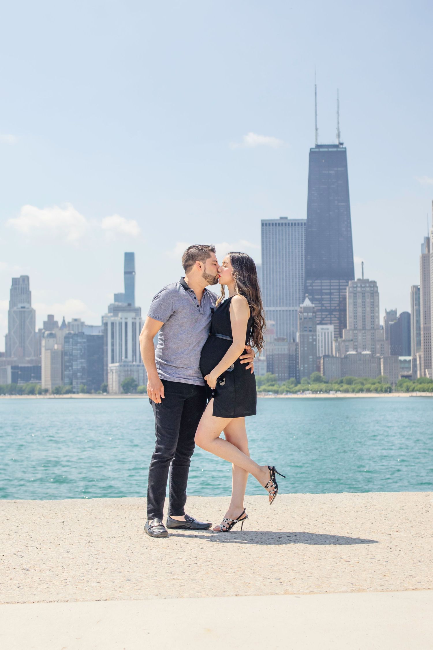 A romantic couple shares a kiss with Chicago's iconic skyline and Lake Michigan in the background.