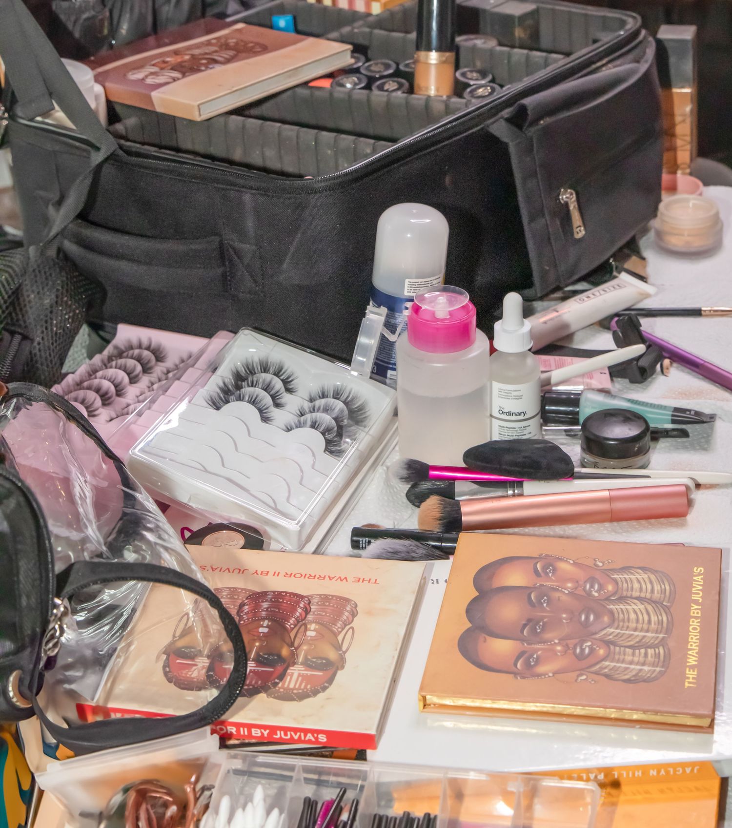 Makeup station with cosmetics, brushes, and beauty supplies laid out on table.