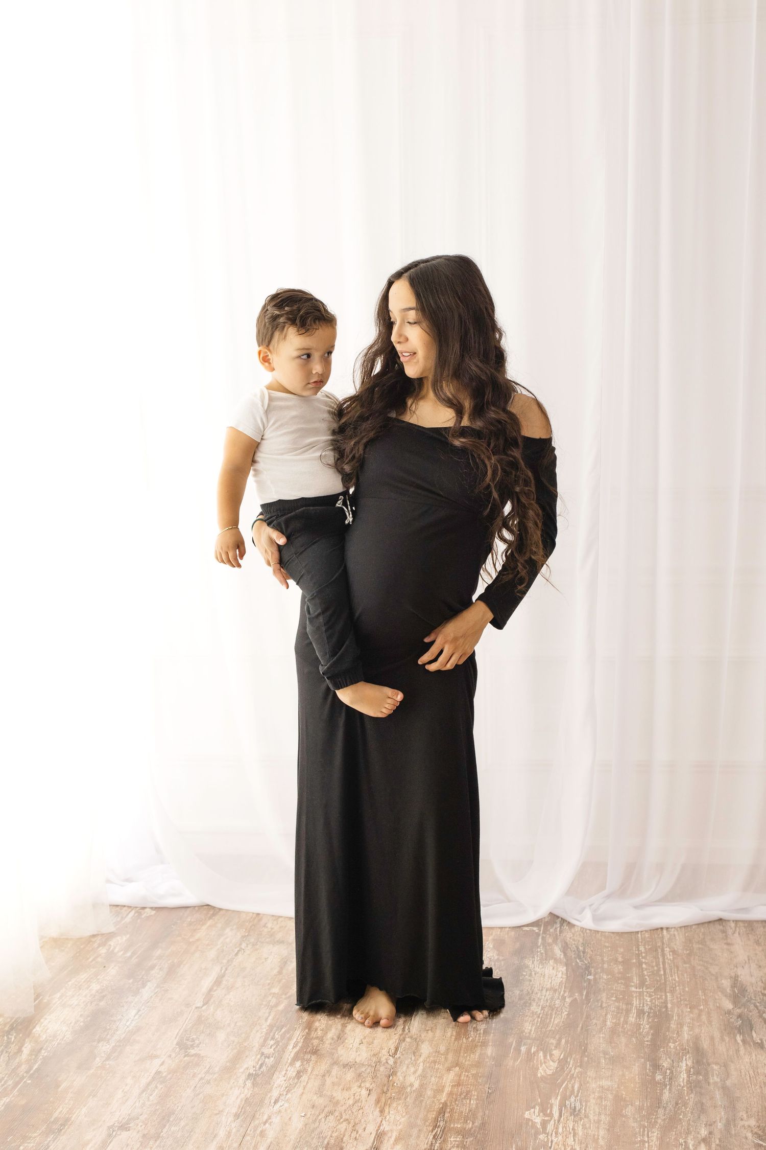 A series of tender moments between a parent and toddler wearing contrasting black and white outfits against a light backdrop.