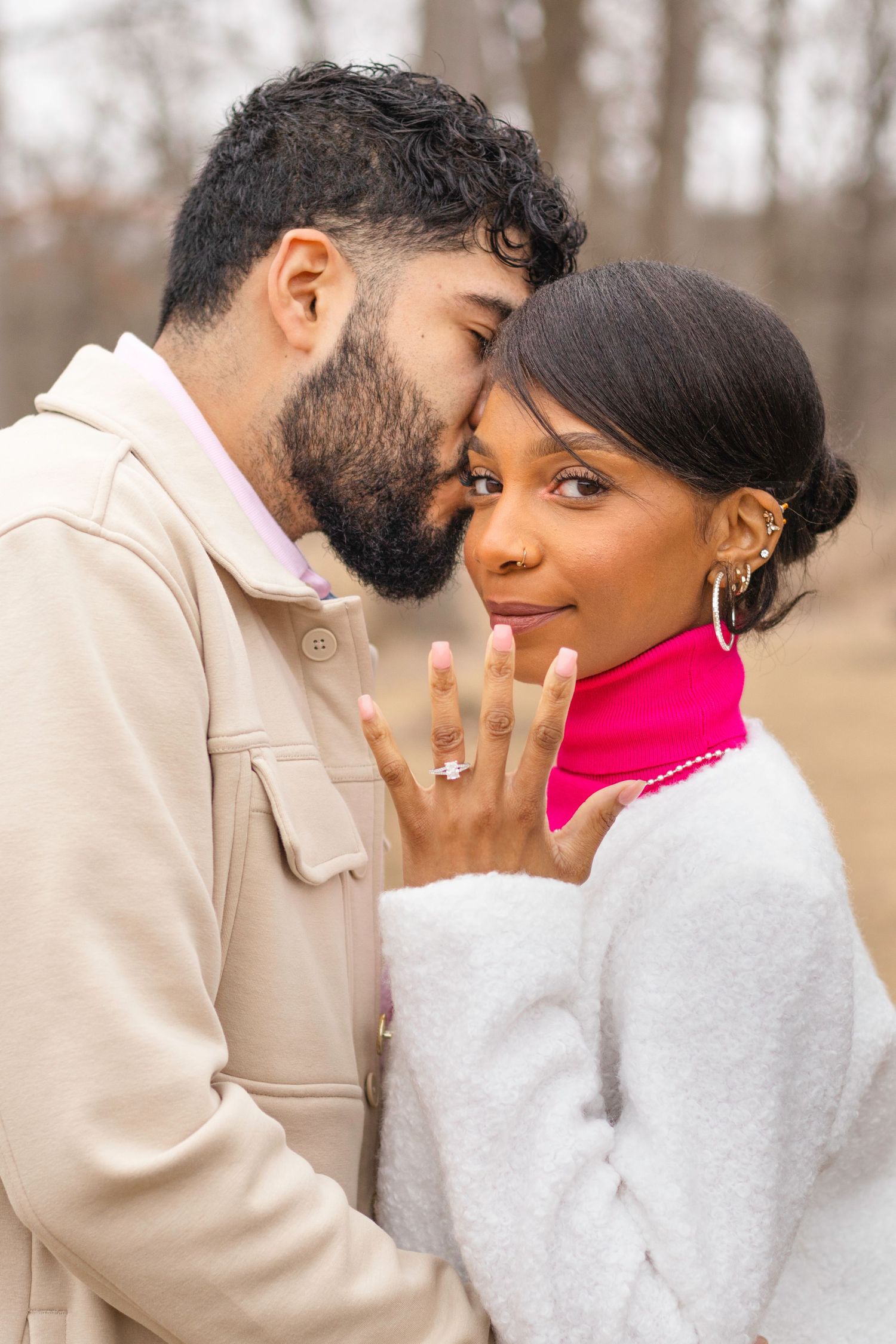 An engaged couple share an intimate moment while showing off a new engagement ring.