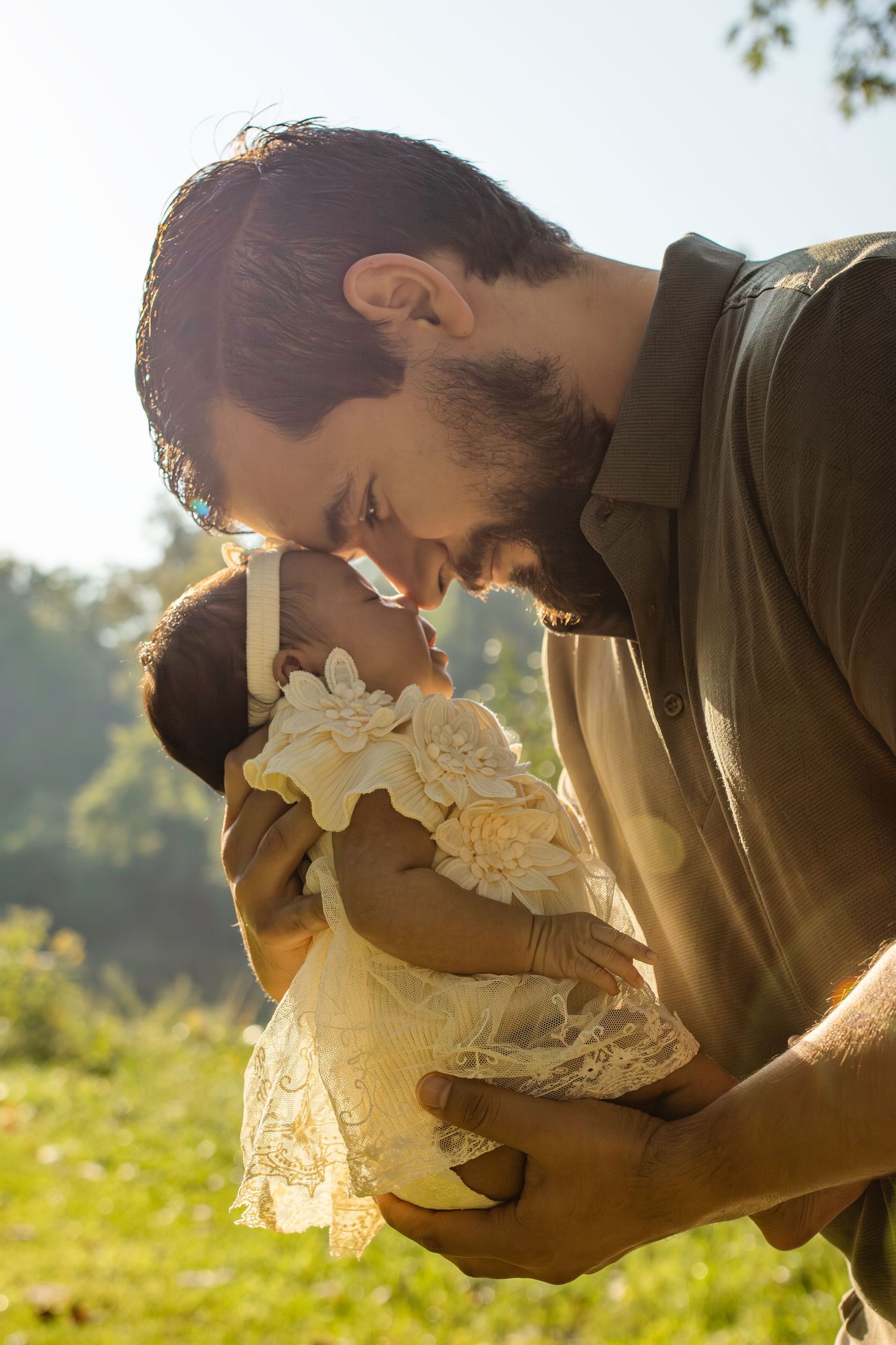 Person smelling a large white mushroom in sunlit forest during golden hour.