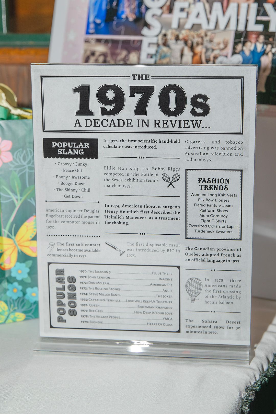A vintage 1970s decade in review sign displayed at an event, featuring popular slang, songs, and fashion trends.