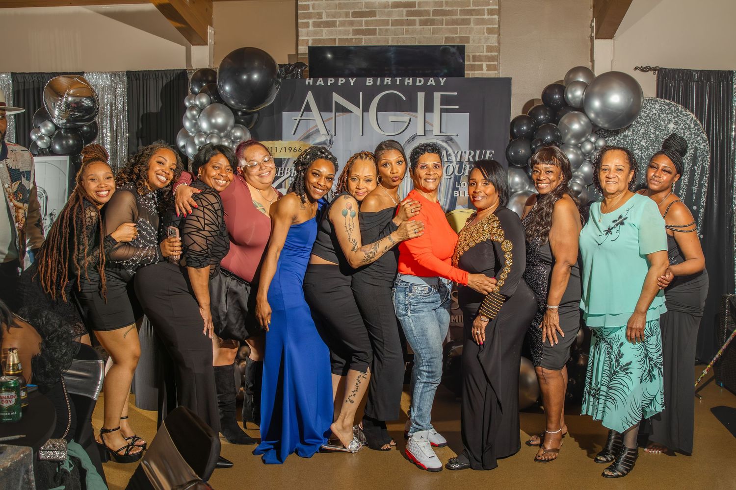Group of women posing together at Angie's birthday party with black and gold balloon decorations.