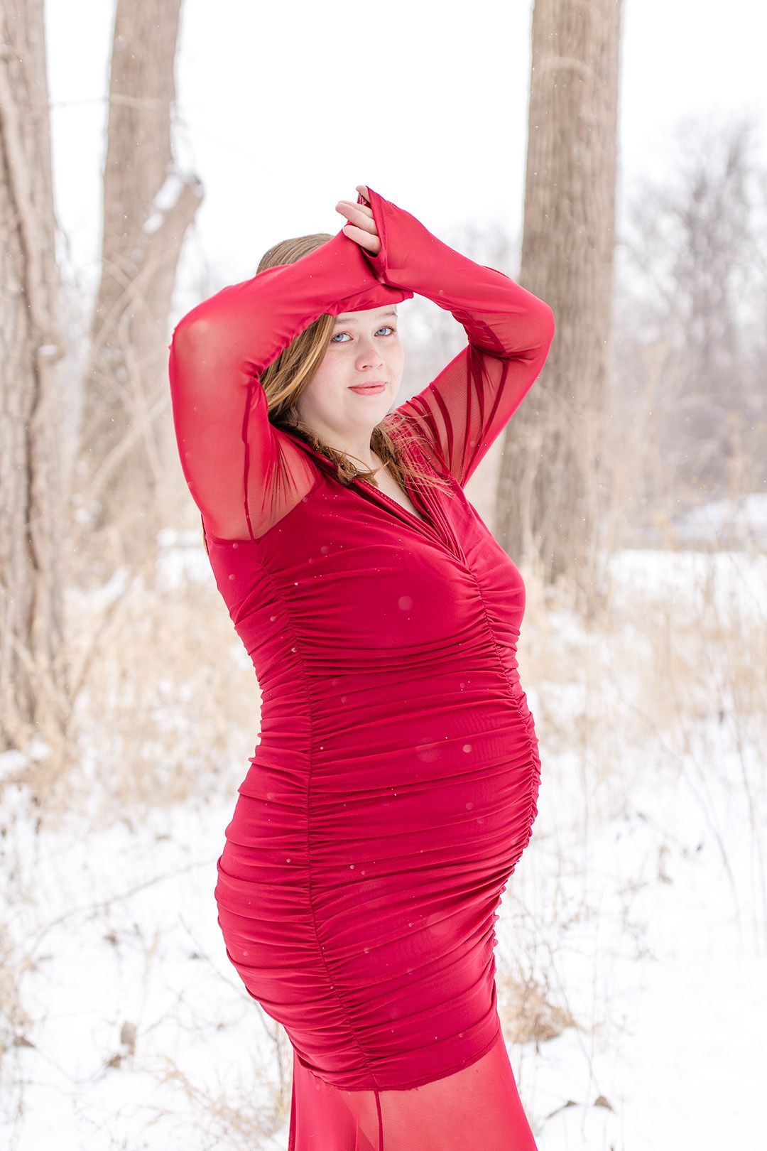 A series of poses in a red maternity dress against a snowy winter forest backdrop.