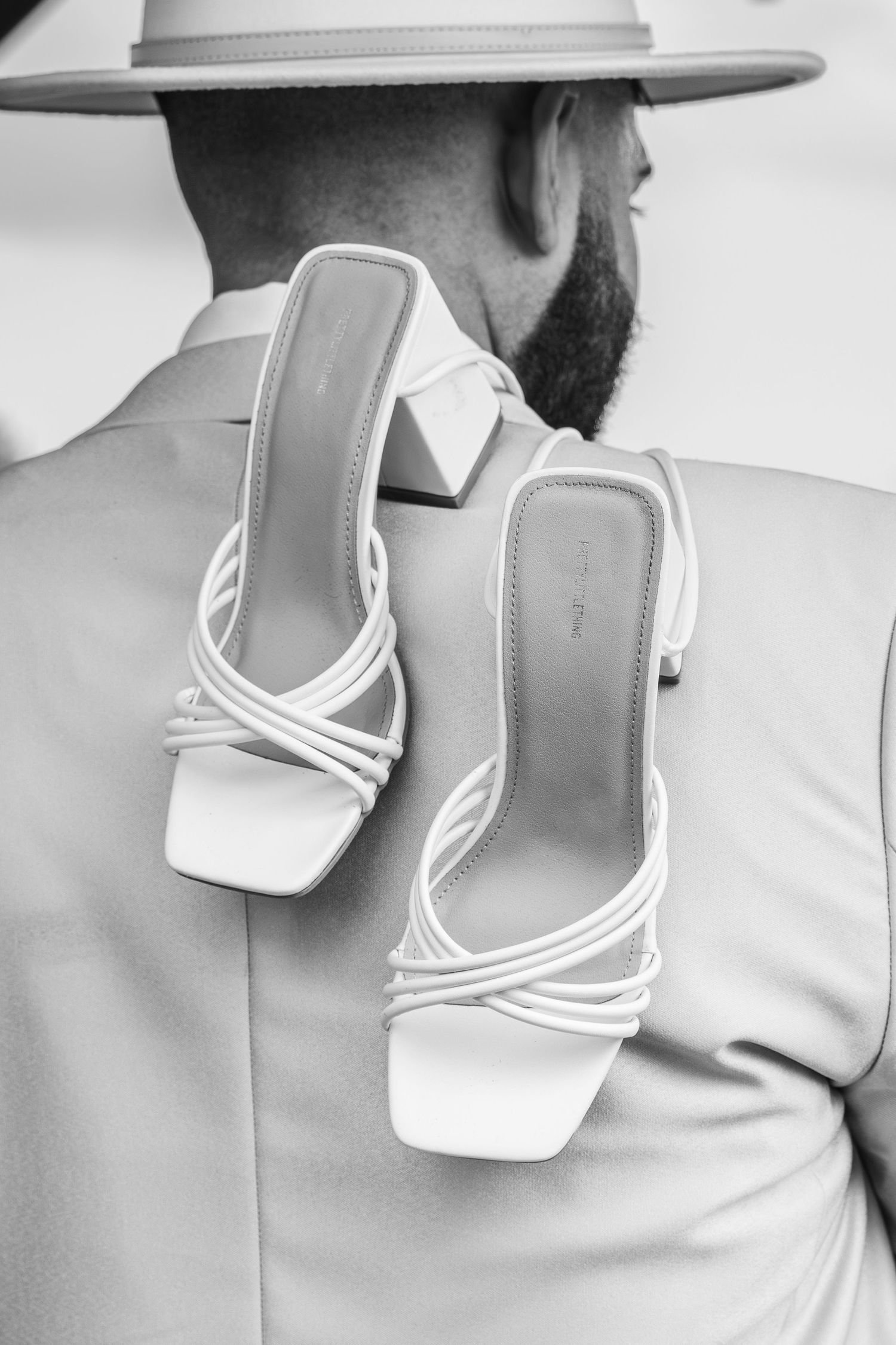 Artistic series of white strappy sandals against light colored clothing.