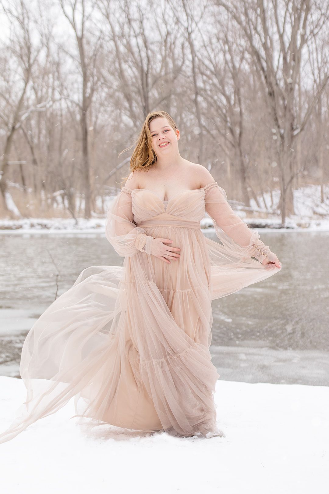 Ethereal maternity portraits in a blush tulle gown set against a snowy winter landscape.