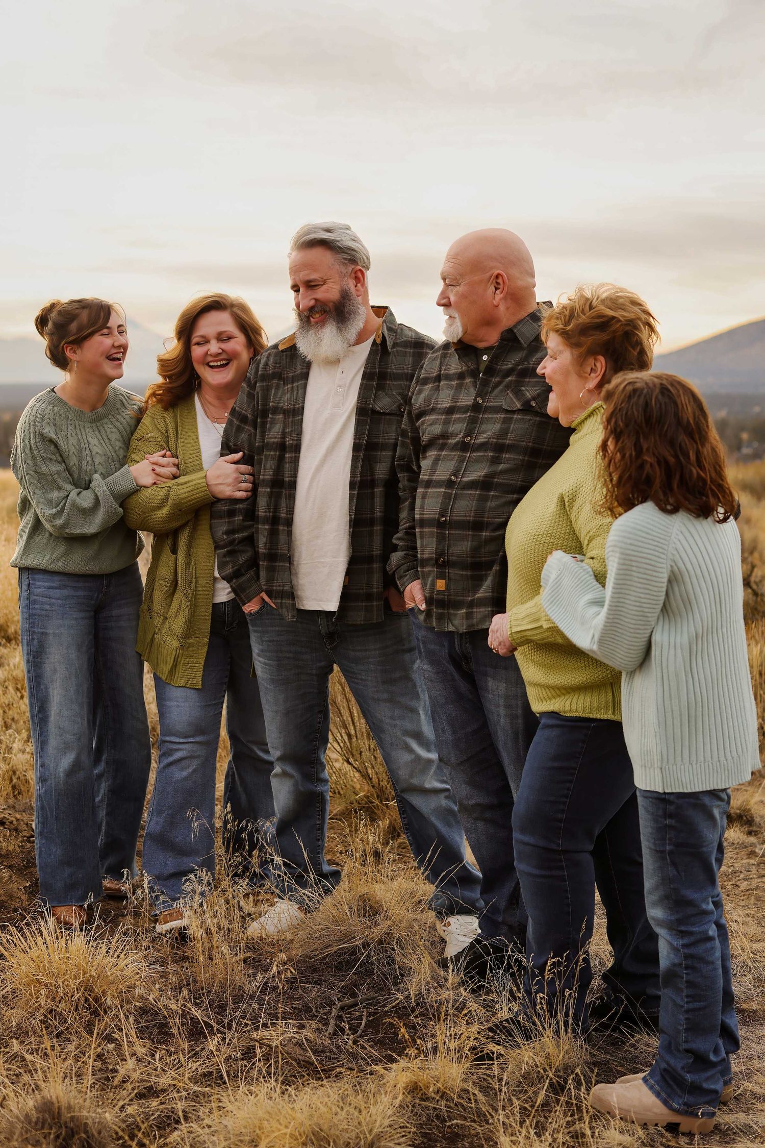 A group of people stand together in casual attire against a scenic outdoor backdrop at sunset.