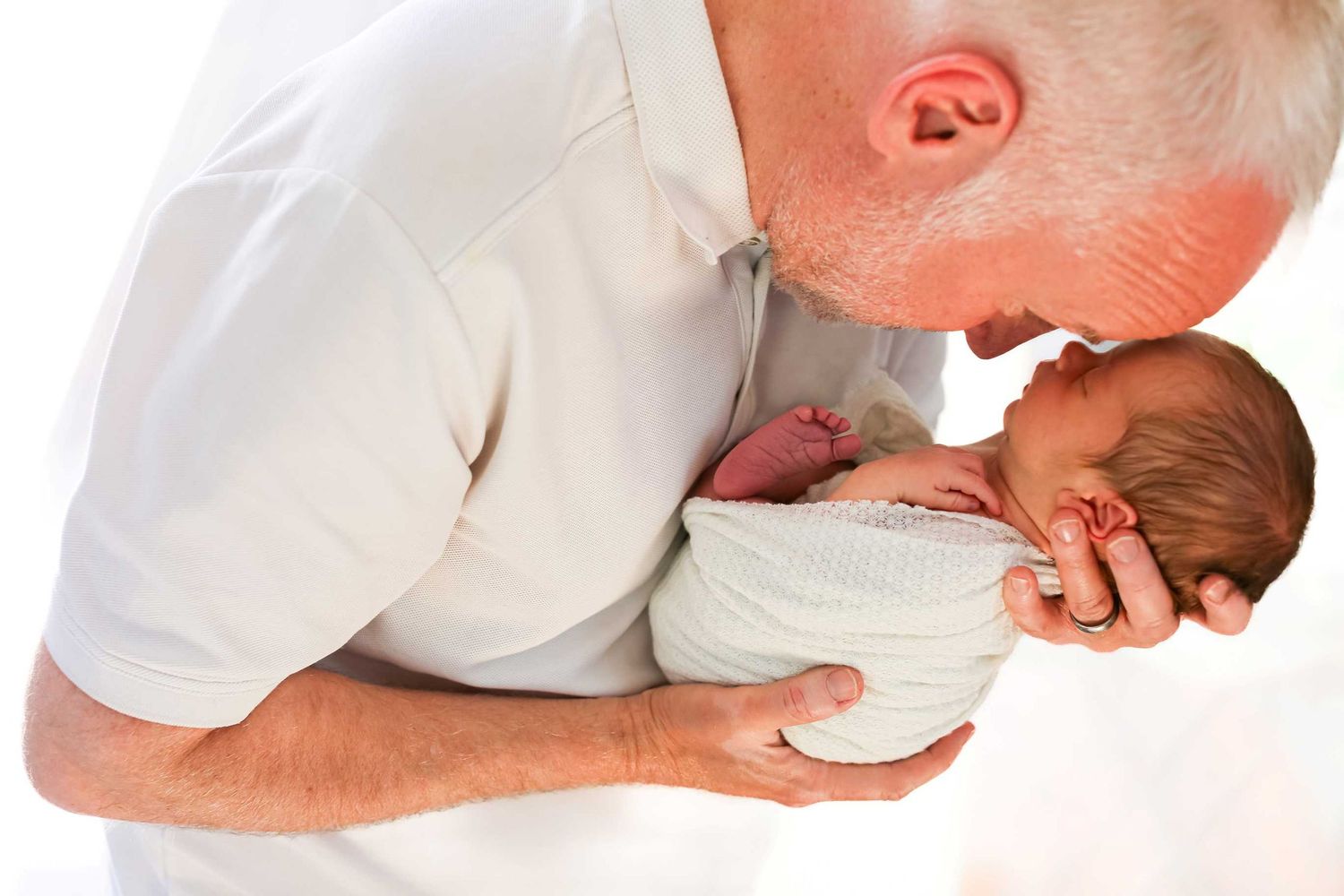 Side view of newborn being gently cradled during professional photo session.