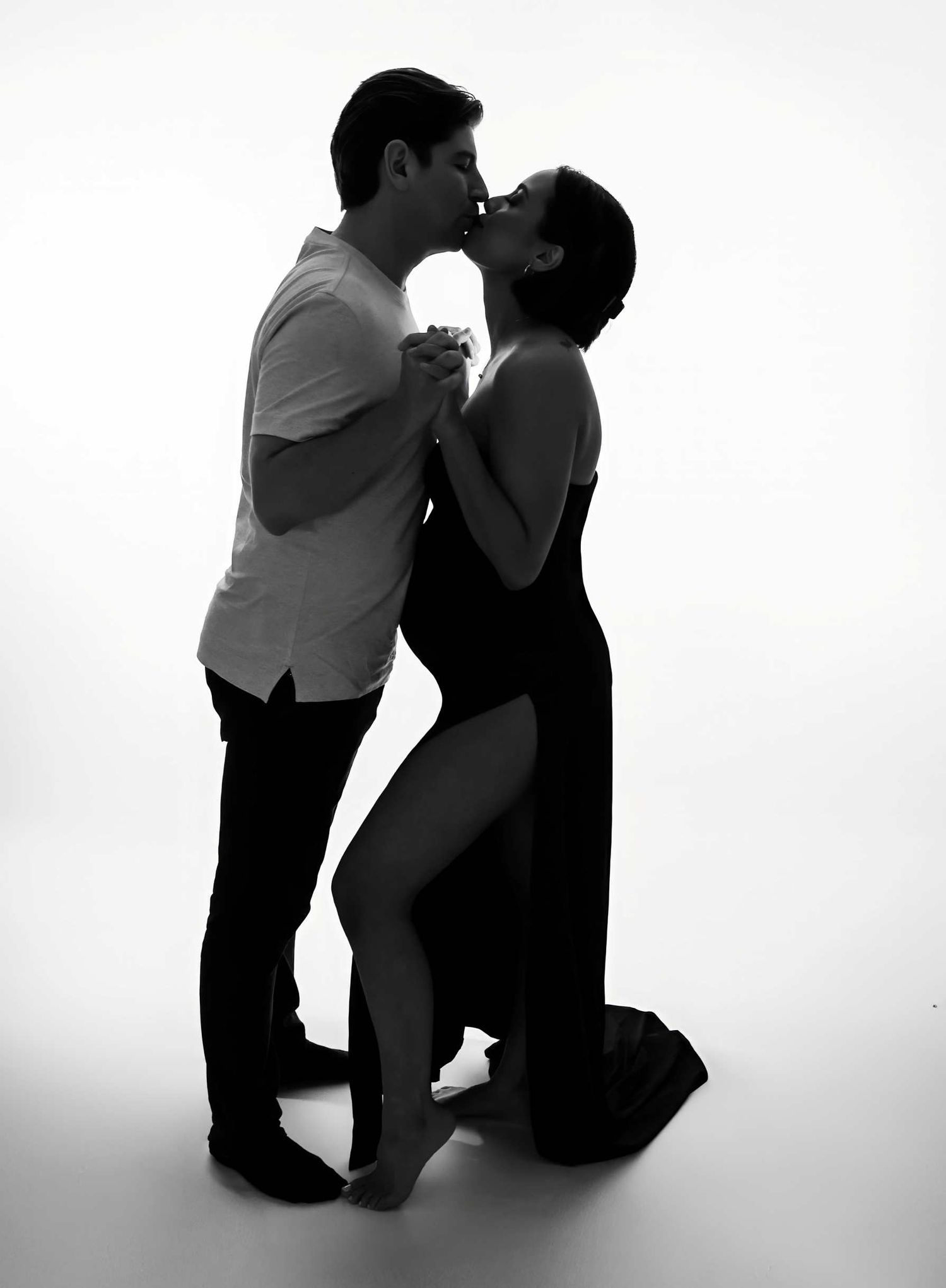 Romantic silhouette of couple in tender embrace during maternity photo session.
