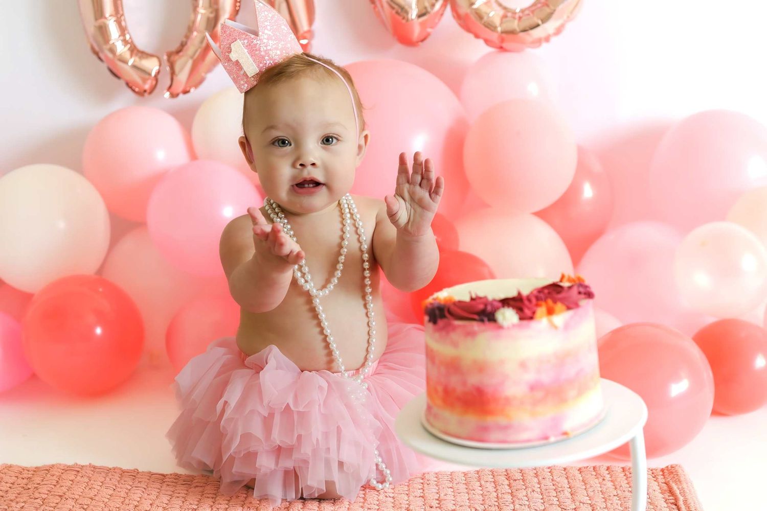 First birthday celebration setup with pink balloons and tulle tutu decorations for cake smash photoshoot.