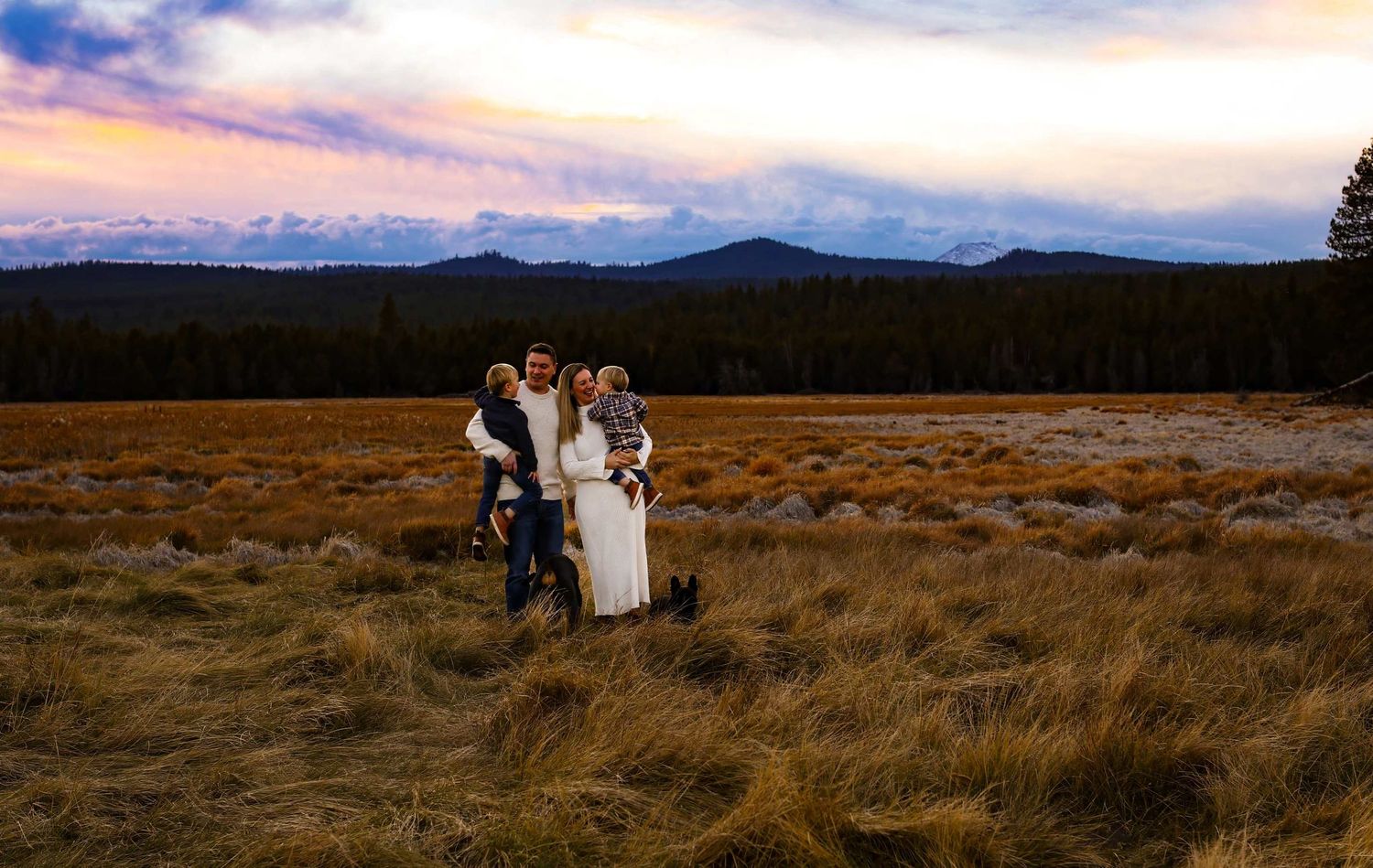 Small group standing together in a mountain meadow at sunset.