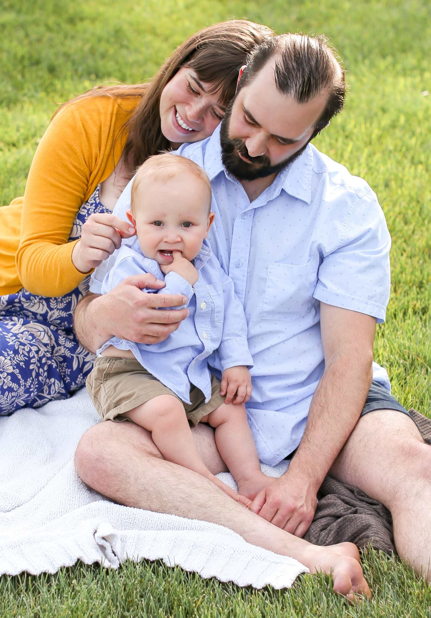 A family sits together on a white blanket in the grass on a sunny summer day. Black Butte Ranch, Sisters Oregon