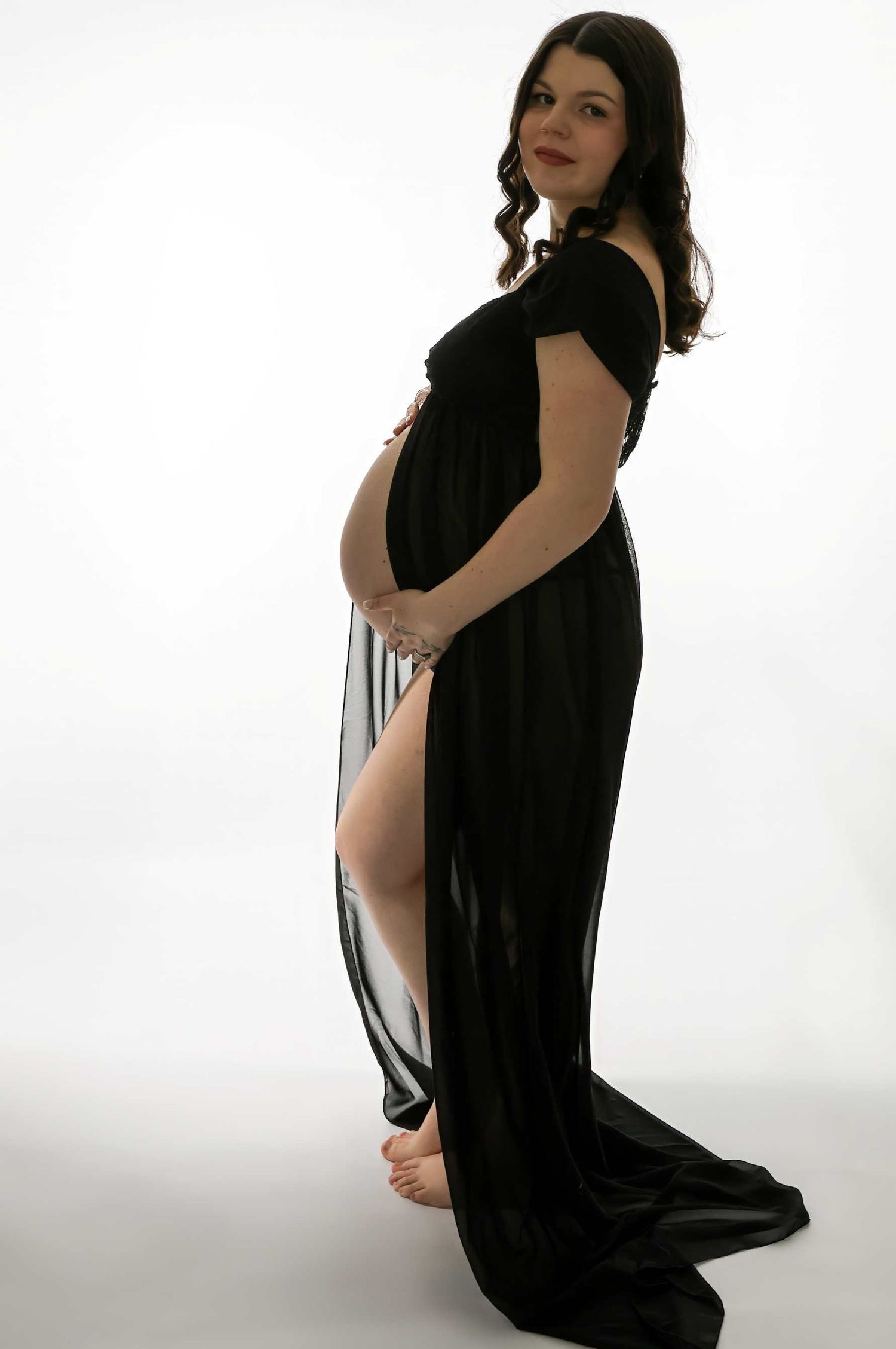 Artistic maternity photo series with woman in black dress against white background.