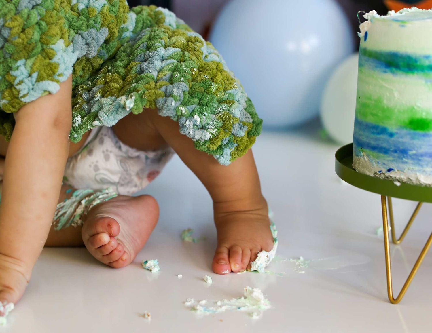 Detail shots of baby's feet and cake during green-themed first birthday photoshoot.