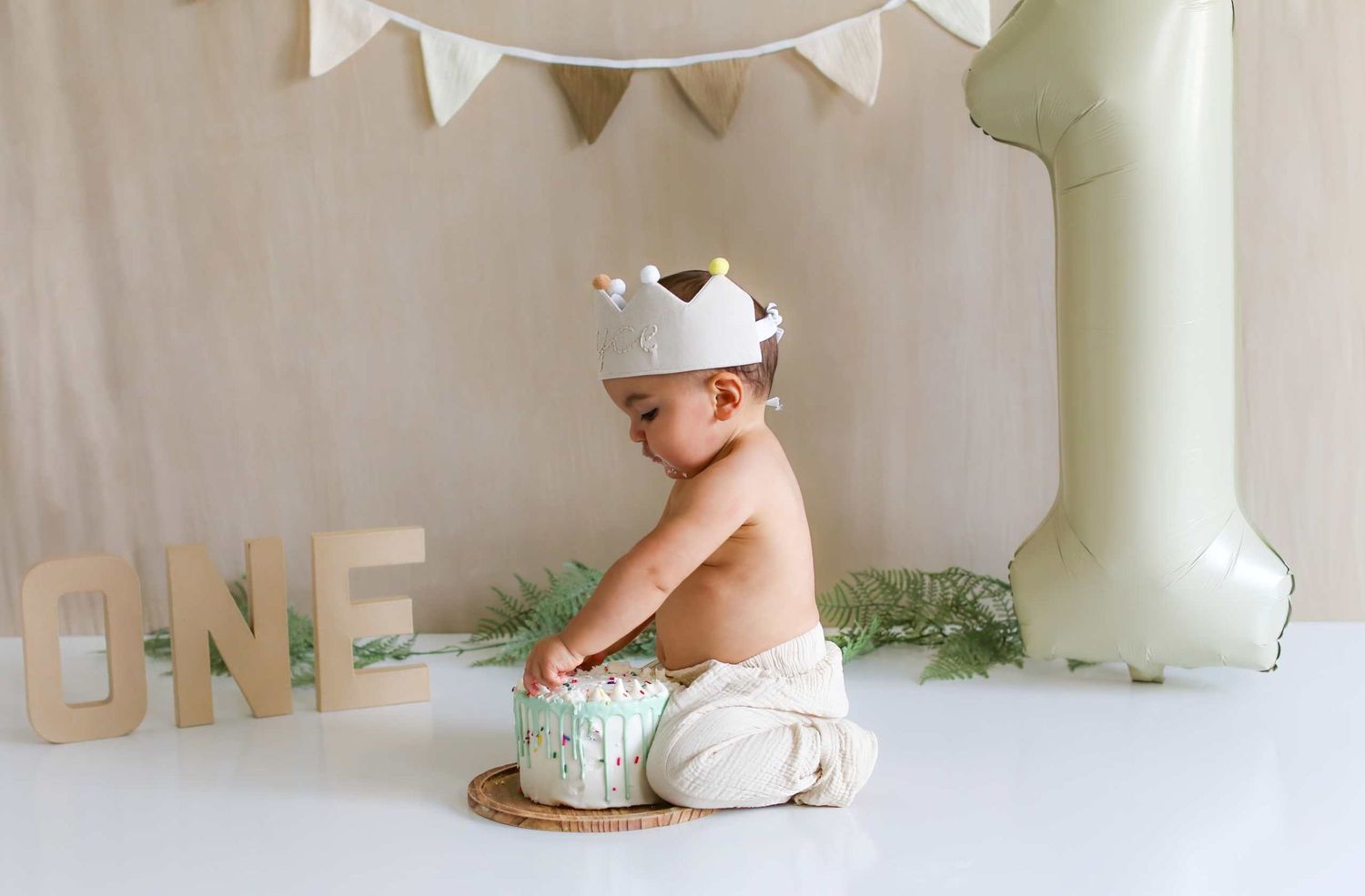 Pastel colored first birthday party setup with white bunting and decorative letters spelling ONE.