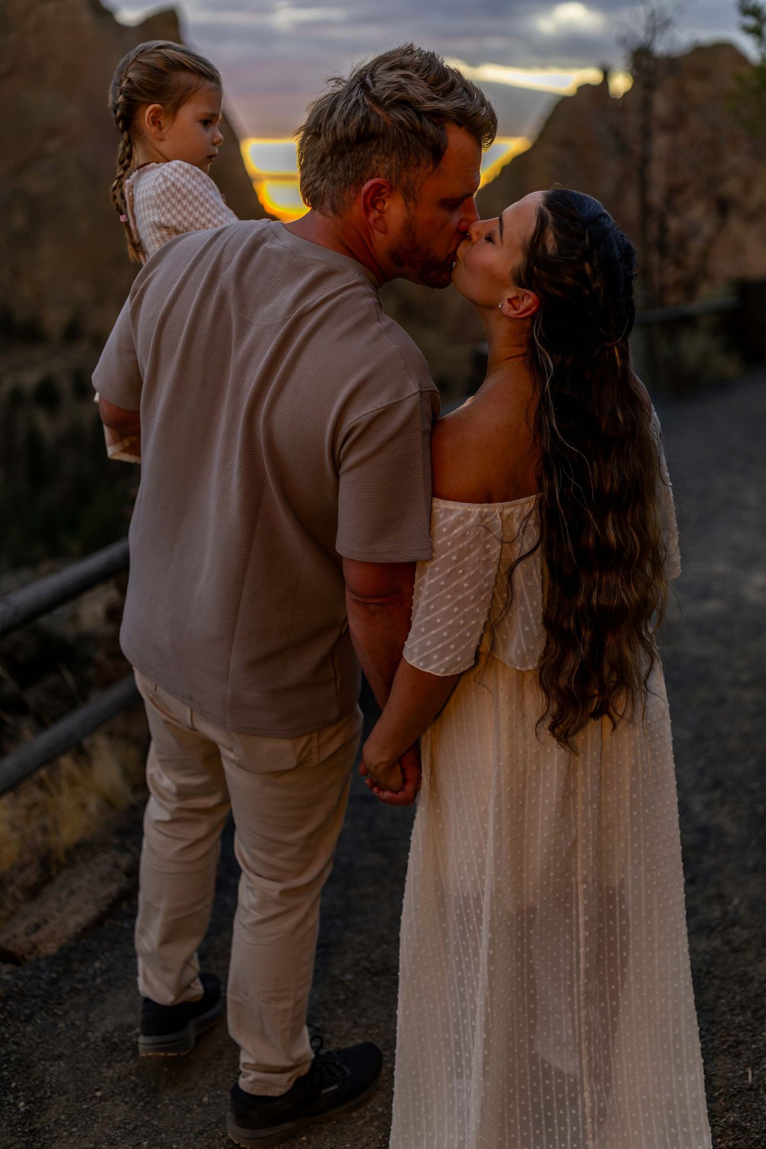 A romantic couple shares an intimate moment at sunset against a moody sky, with multiple frames showing their embrace.