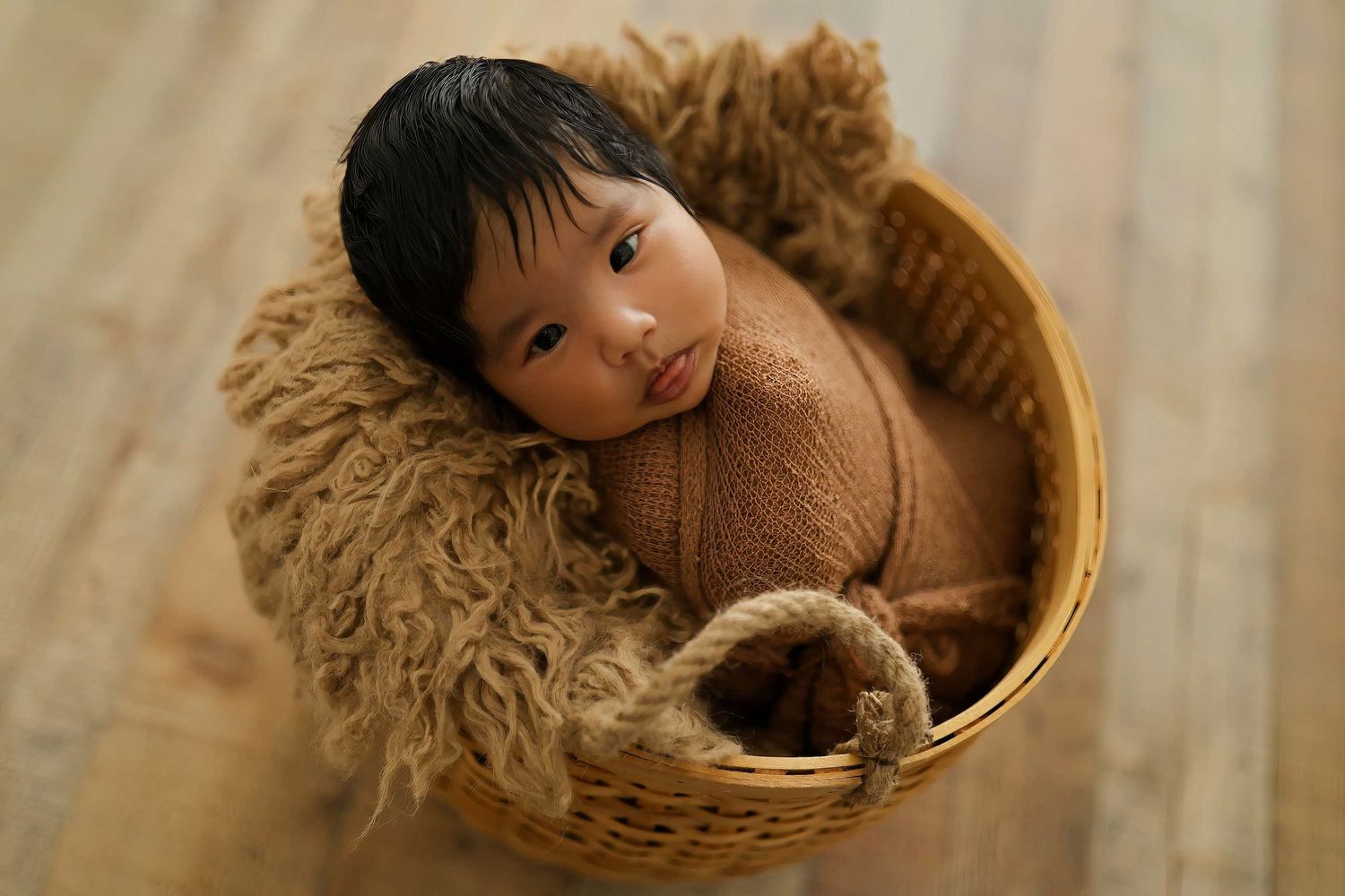 A baby peeks through a round woven basket in a series of four progressive shots.