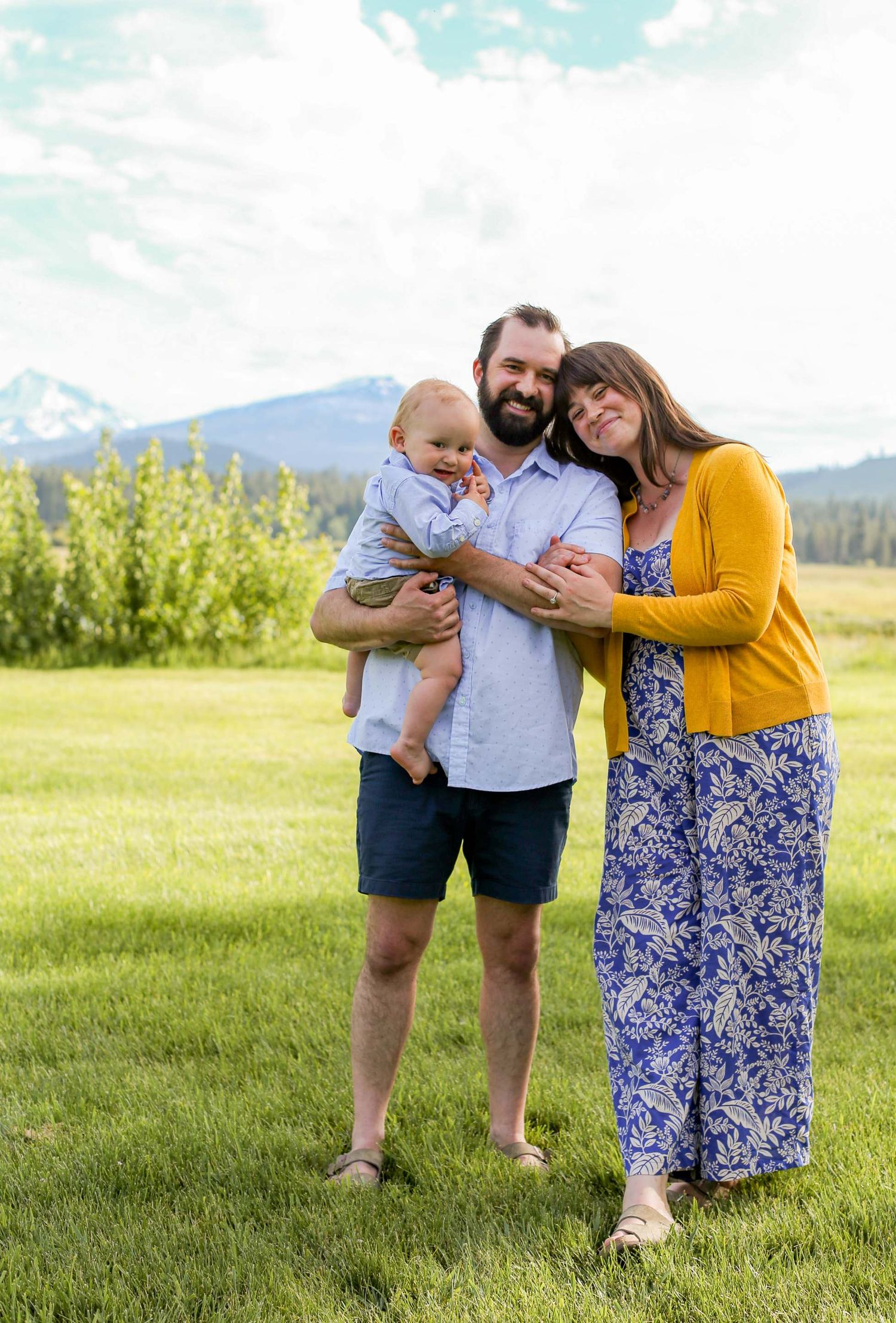 Family spending time together in a sunny mountain meadow with scenic views.