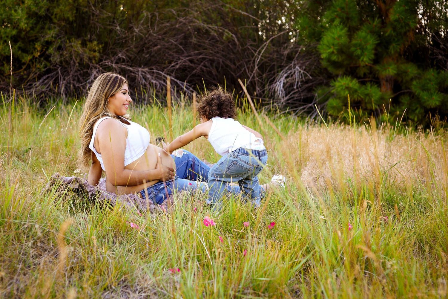 Two people sitting together in a grassy meadow on a sunny afternoon.