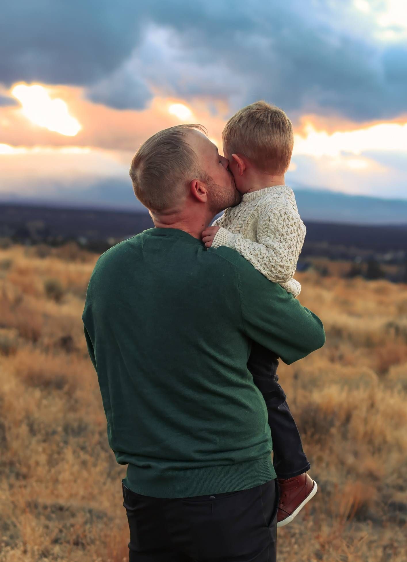 A heartwarming scene of playful interaction between two people against a golden sunset in a desert landscape.